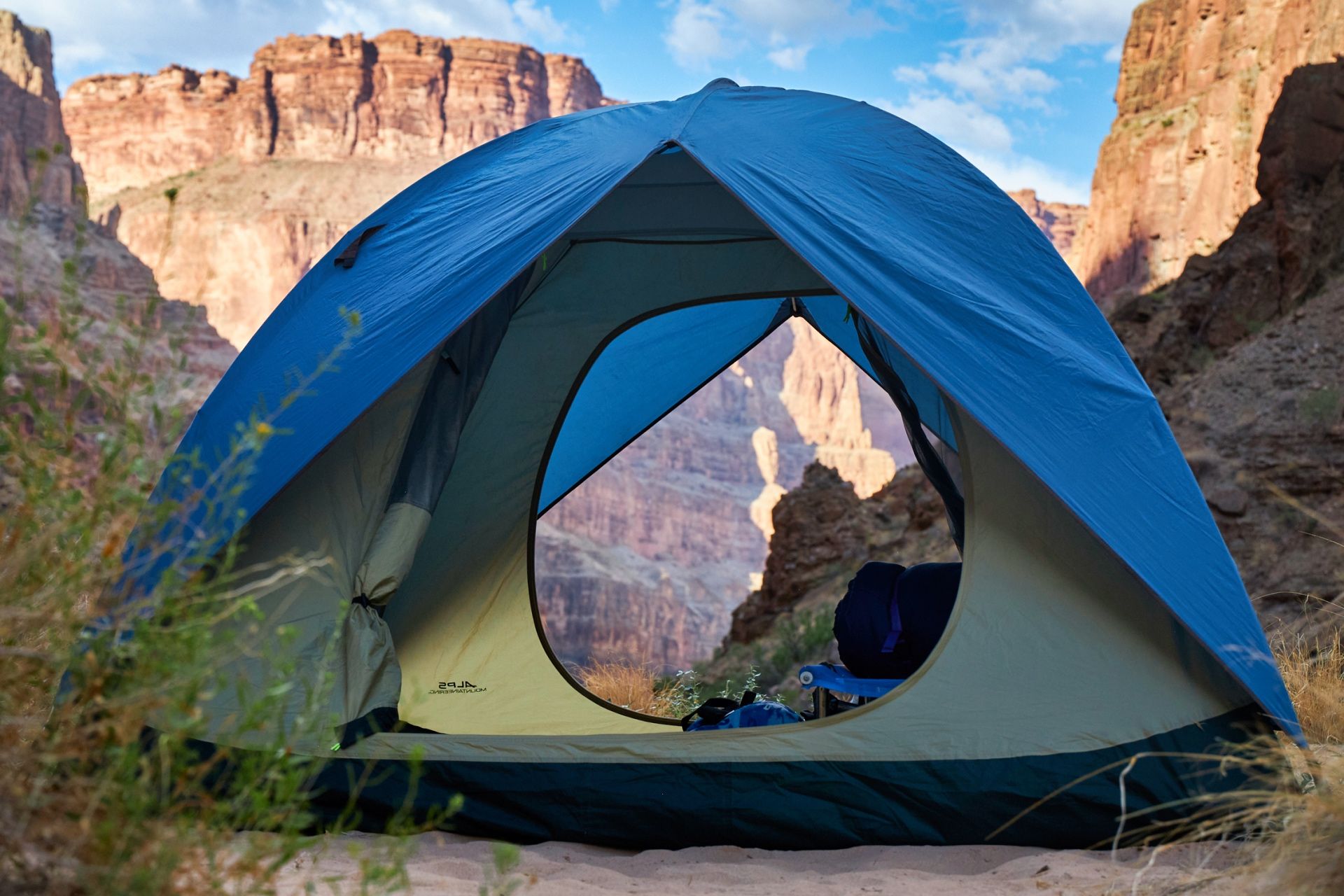 Blue tent facing canyon walls across the river
