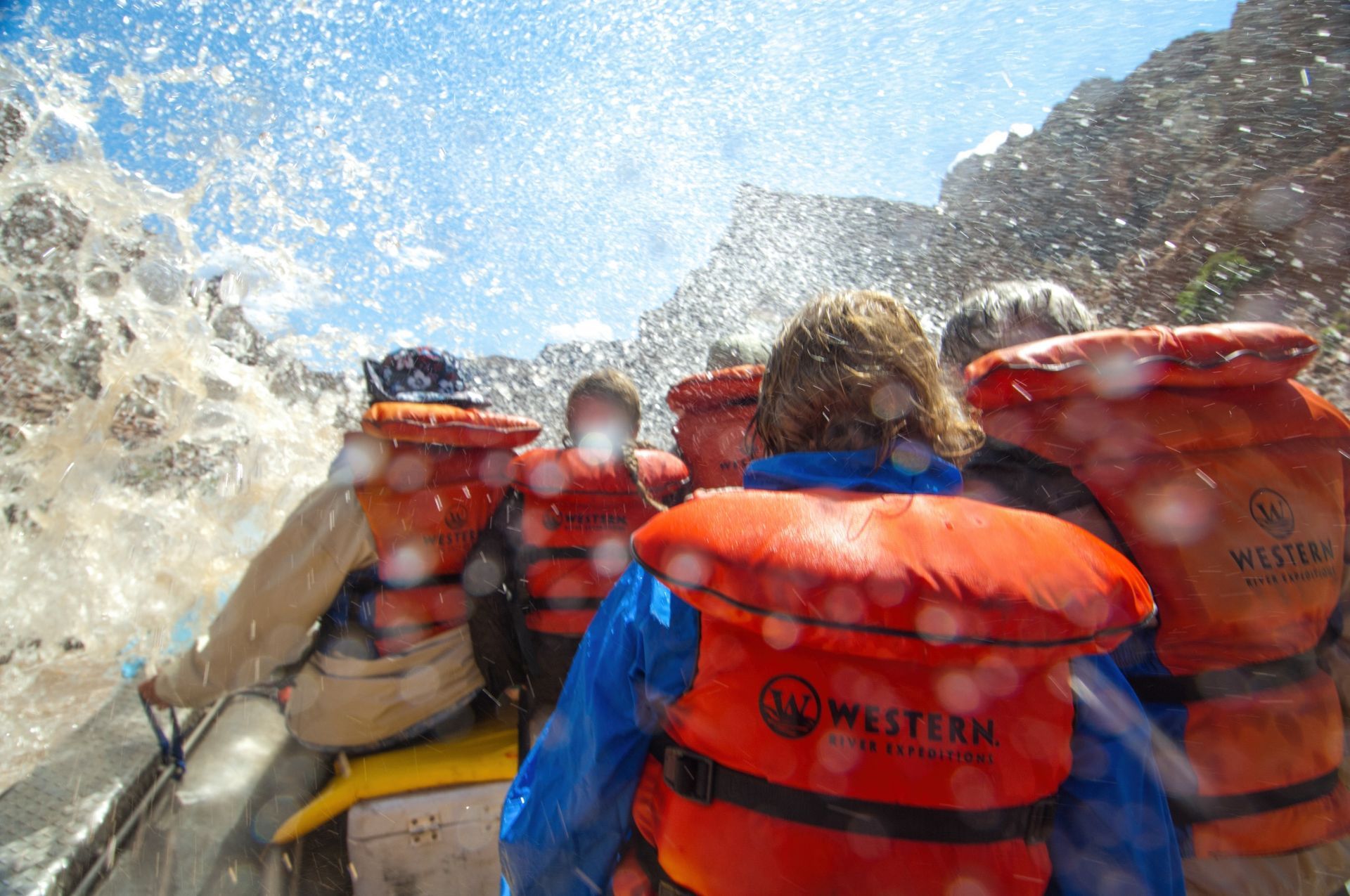 Water splashes over guests at the front of a Cataract Canyon raft