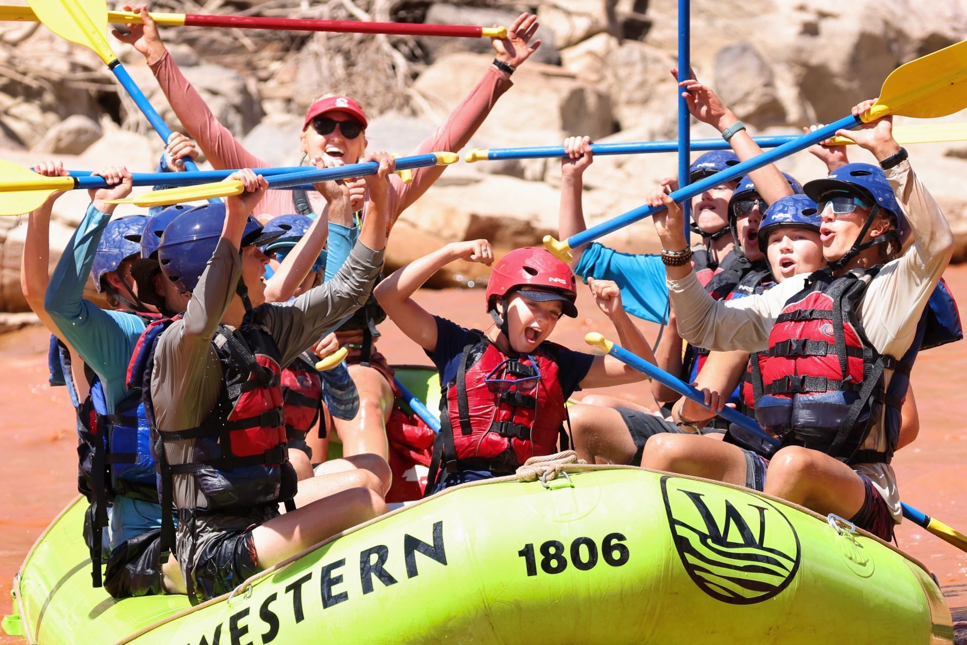 Rafting guests celebrate with their paddles raised