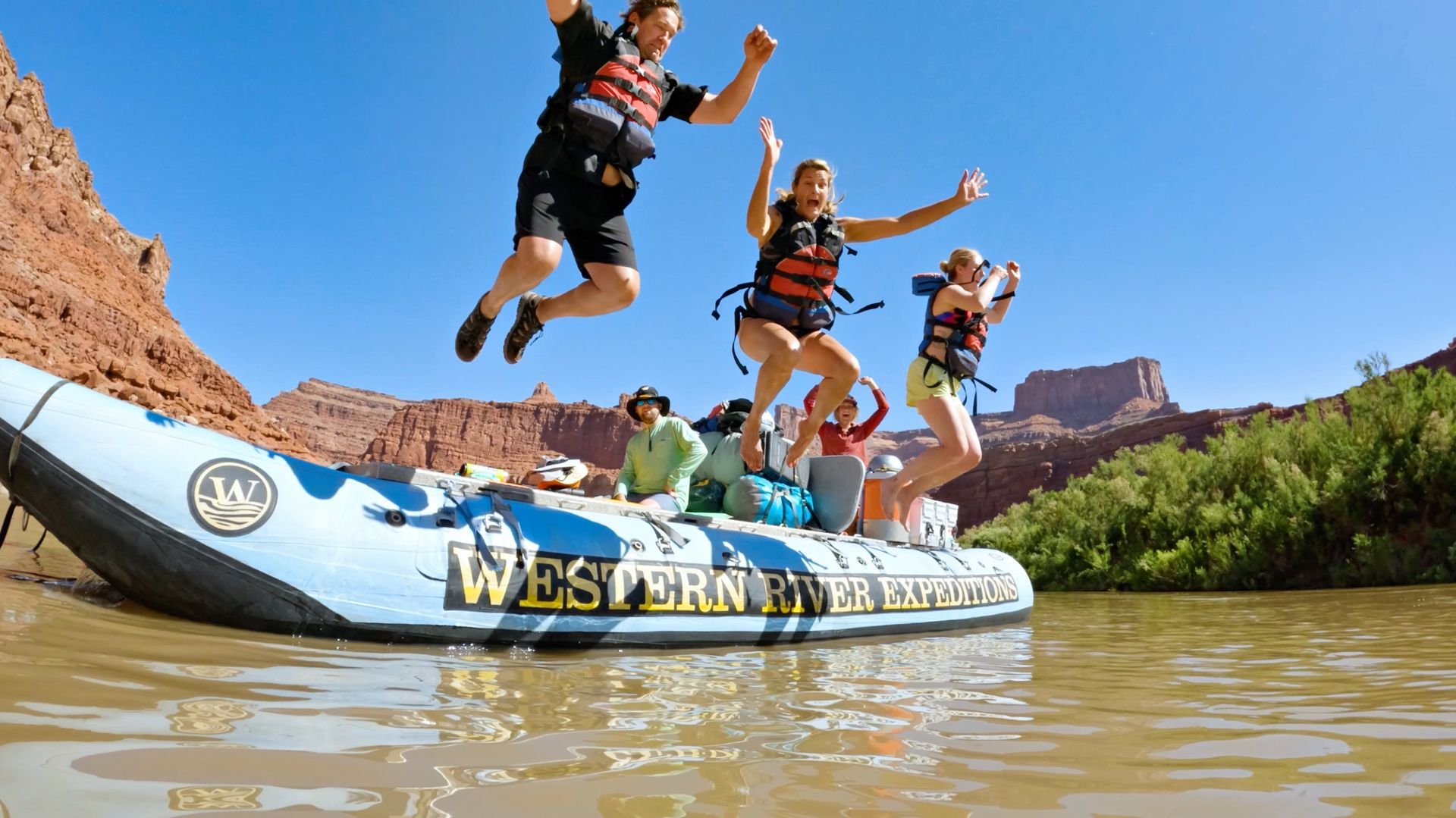 Guests jump from a raft into calm river water
