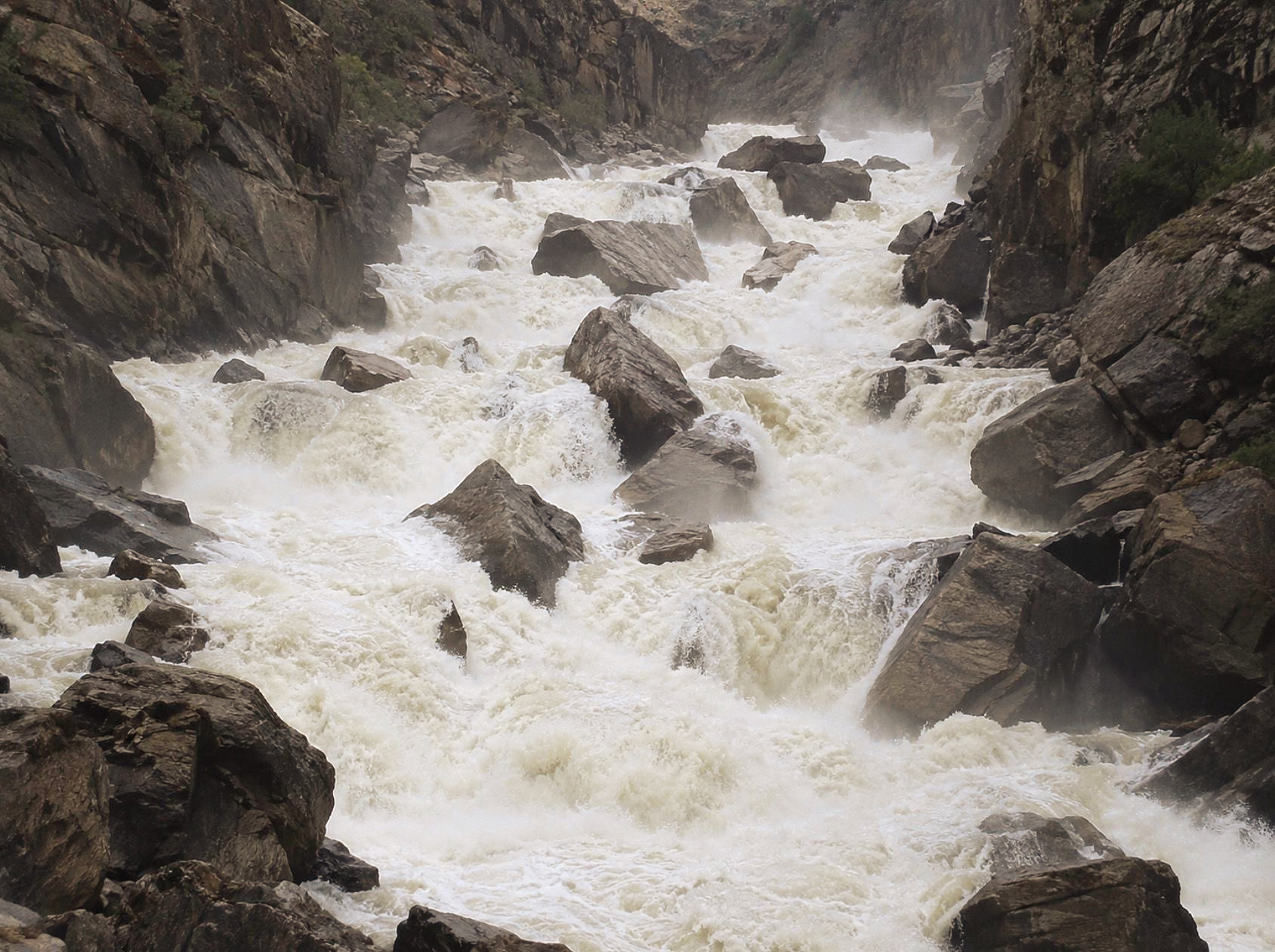 Whitewater cascades through a boulder-filled river channel, depicting Class VI whitewater.