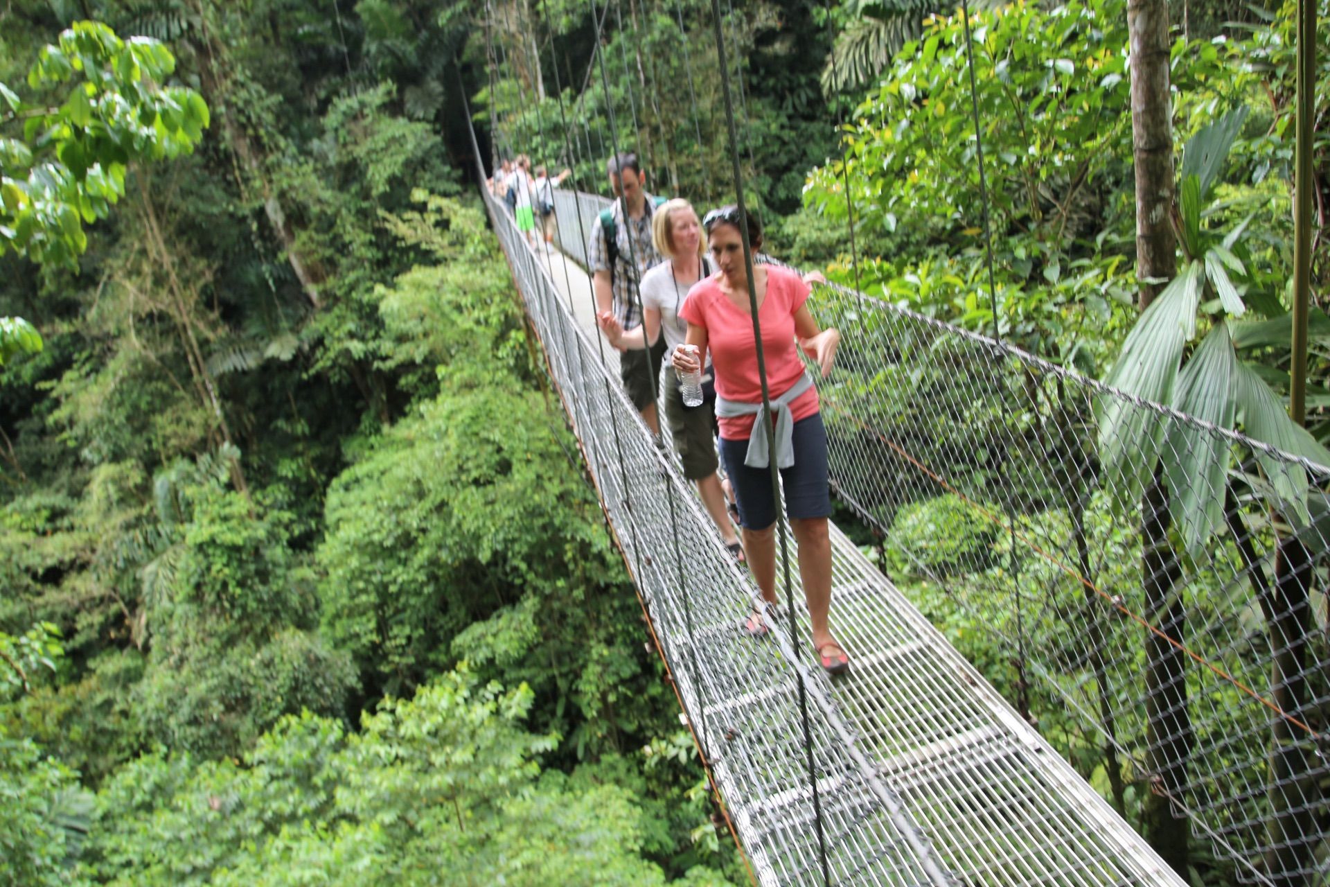 Travelers cross a suspension bridge in a Costa Rica forest