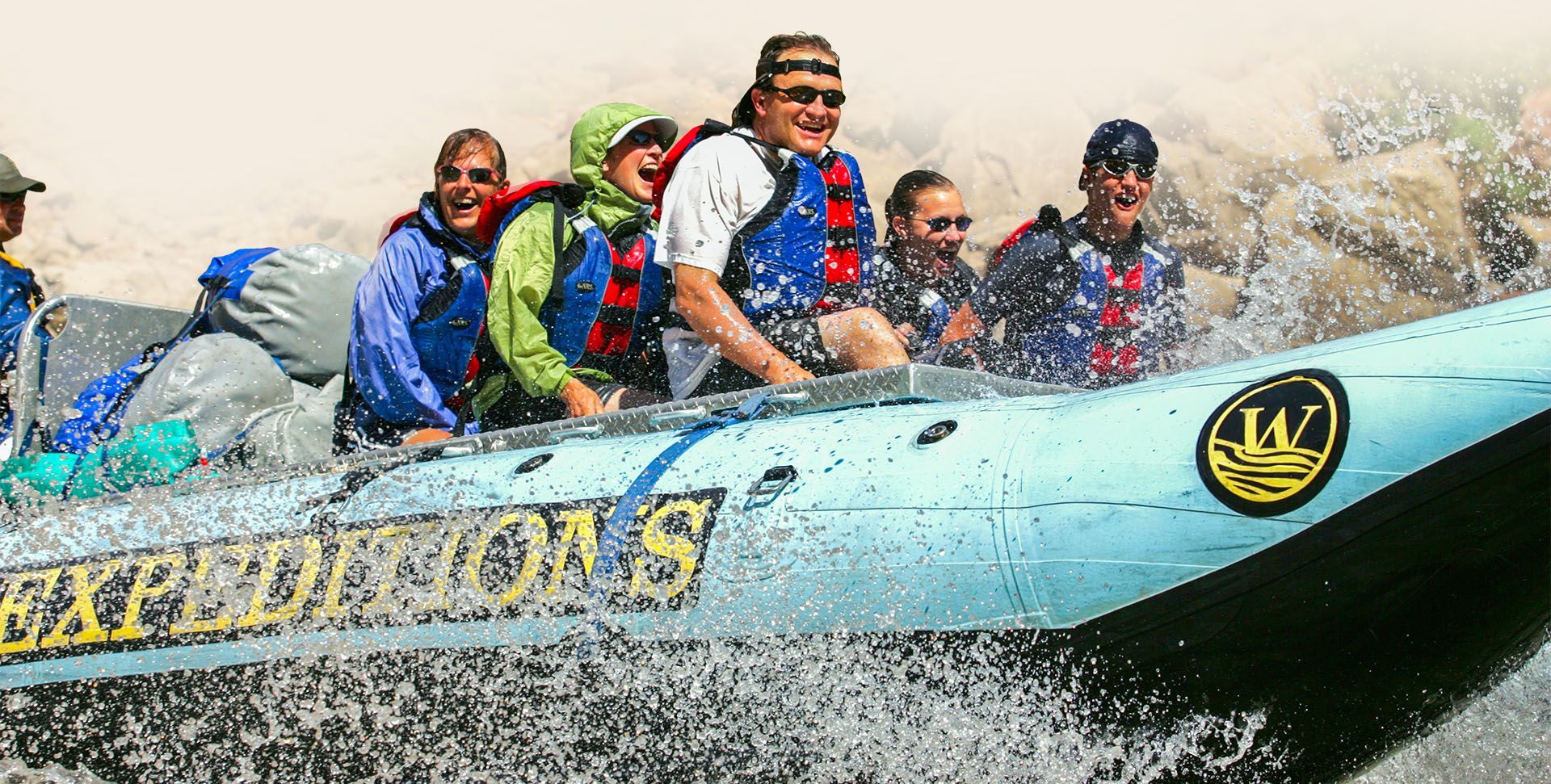 Western River Expeditions snout rig splashes through whitewater with smiling guests 