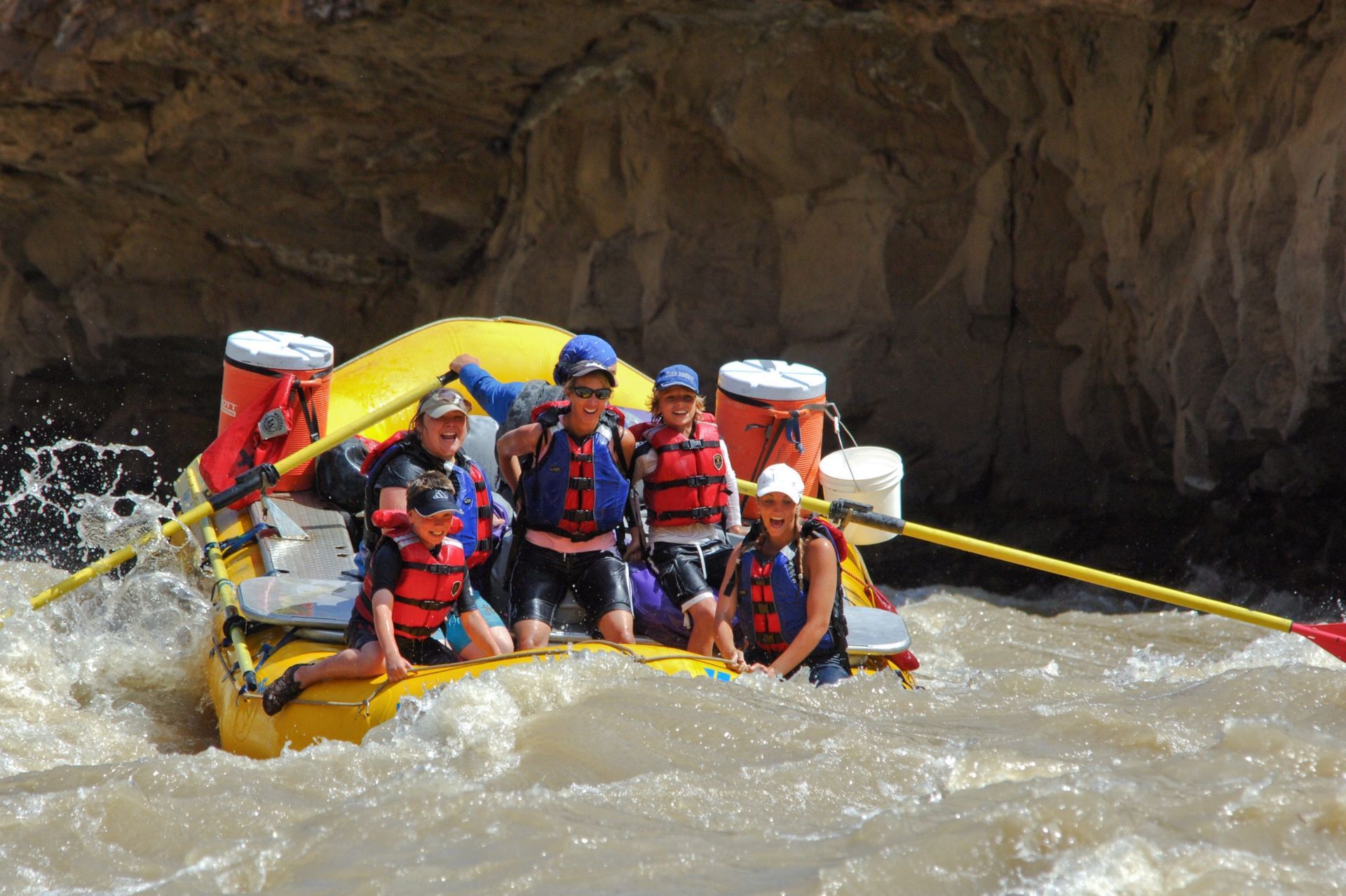 Guests in life jackets smile aboard an oar raft in Desolation Canyon