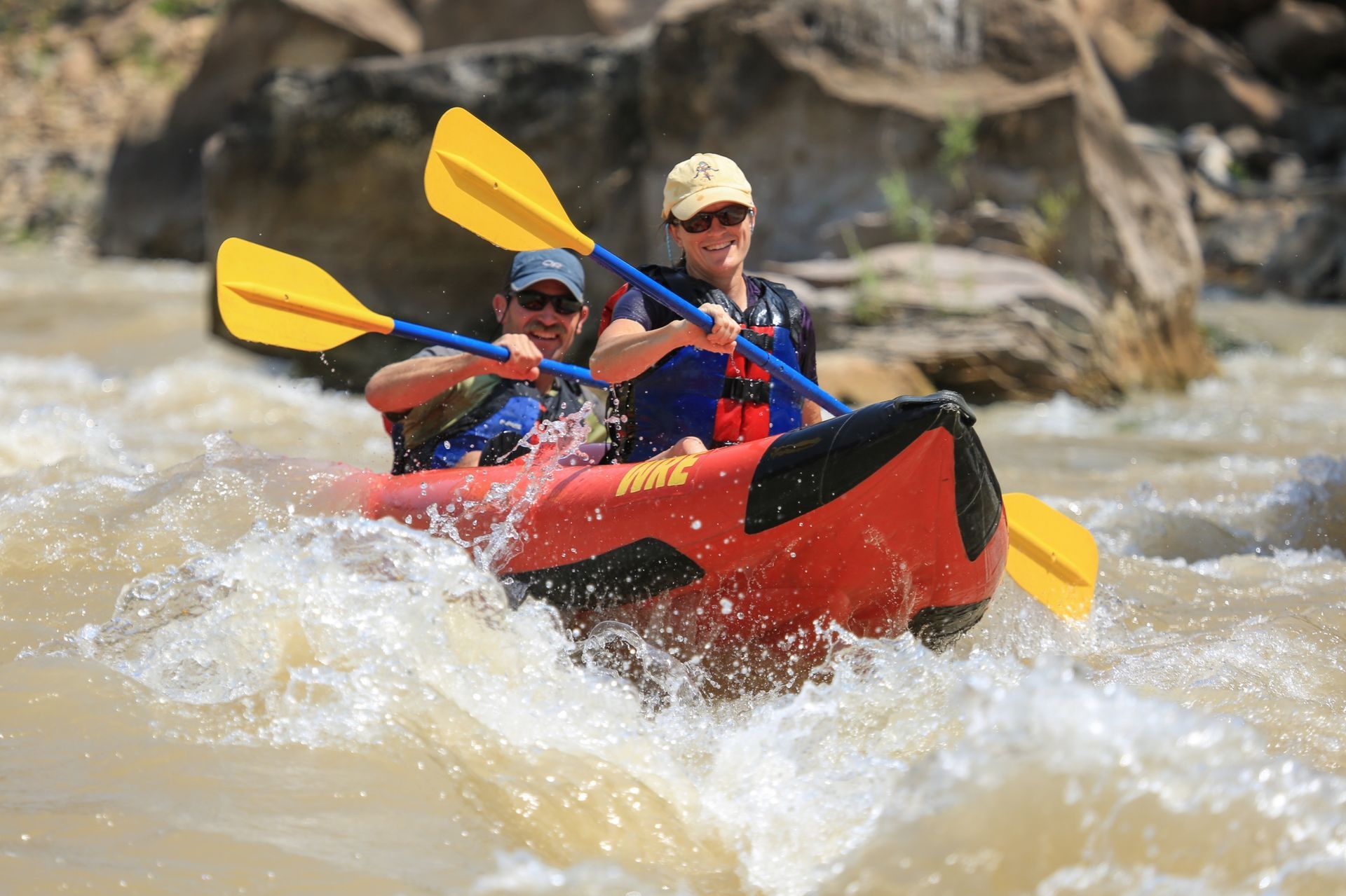 Two paddlers ride an inflatable kayak through Desolation Canyon whitewater