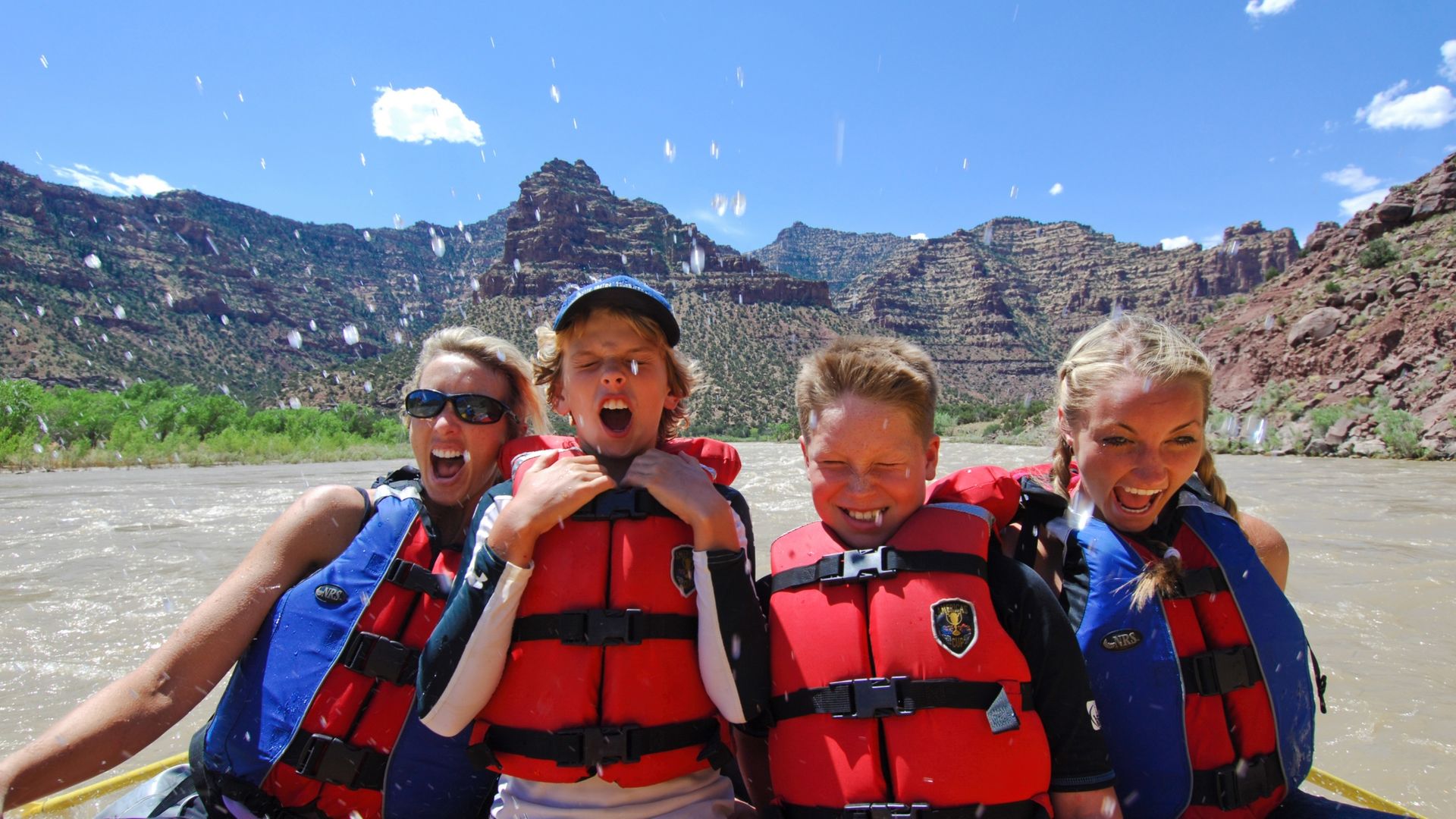 An adult and children smiling together in a raft on the Green River