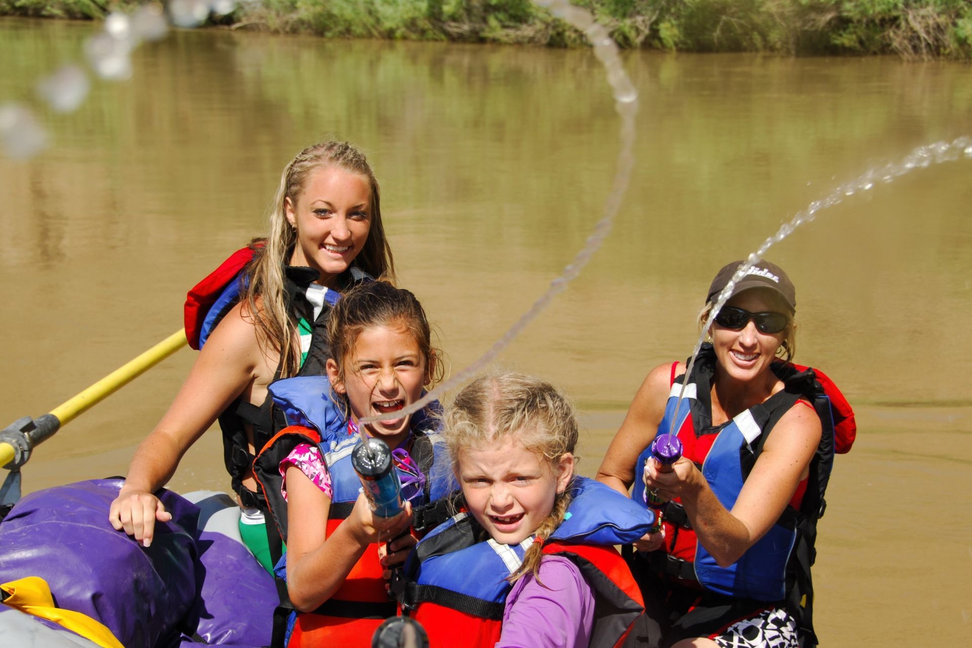 A group splashes water while riding together in an inflatable kayak