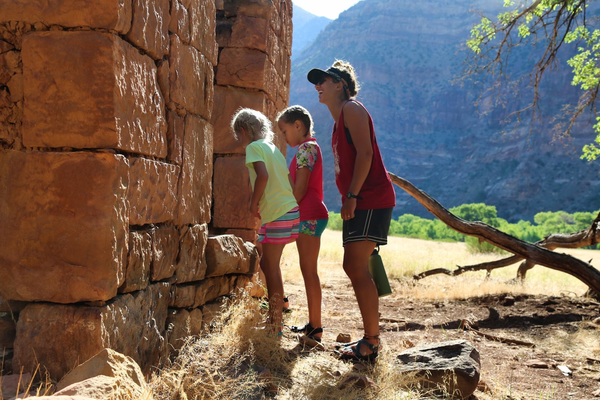 An adult and two children exploring a stone building at Rock Creek Ranch