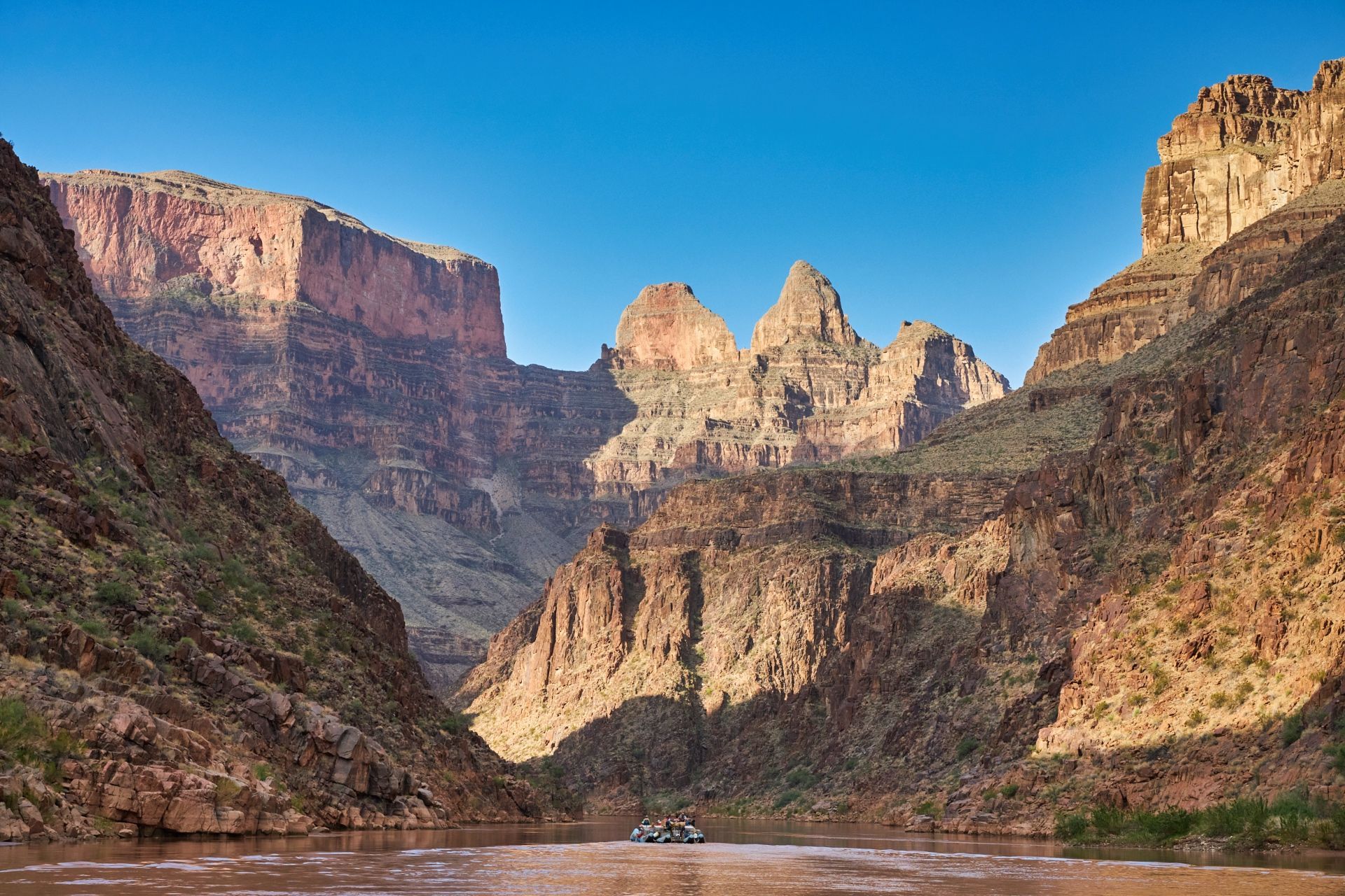 The Colorado River flowing between Grand Canyon’s layered cliffs