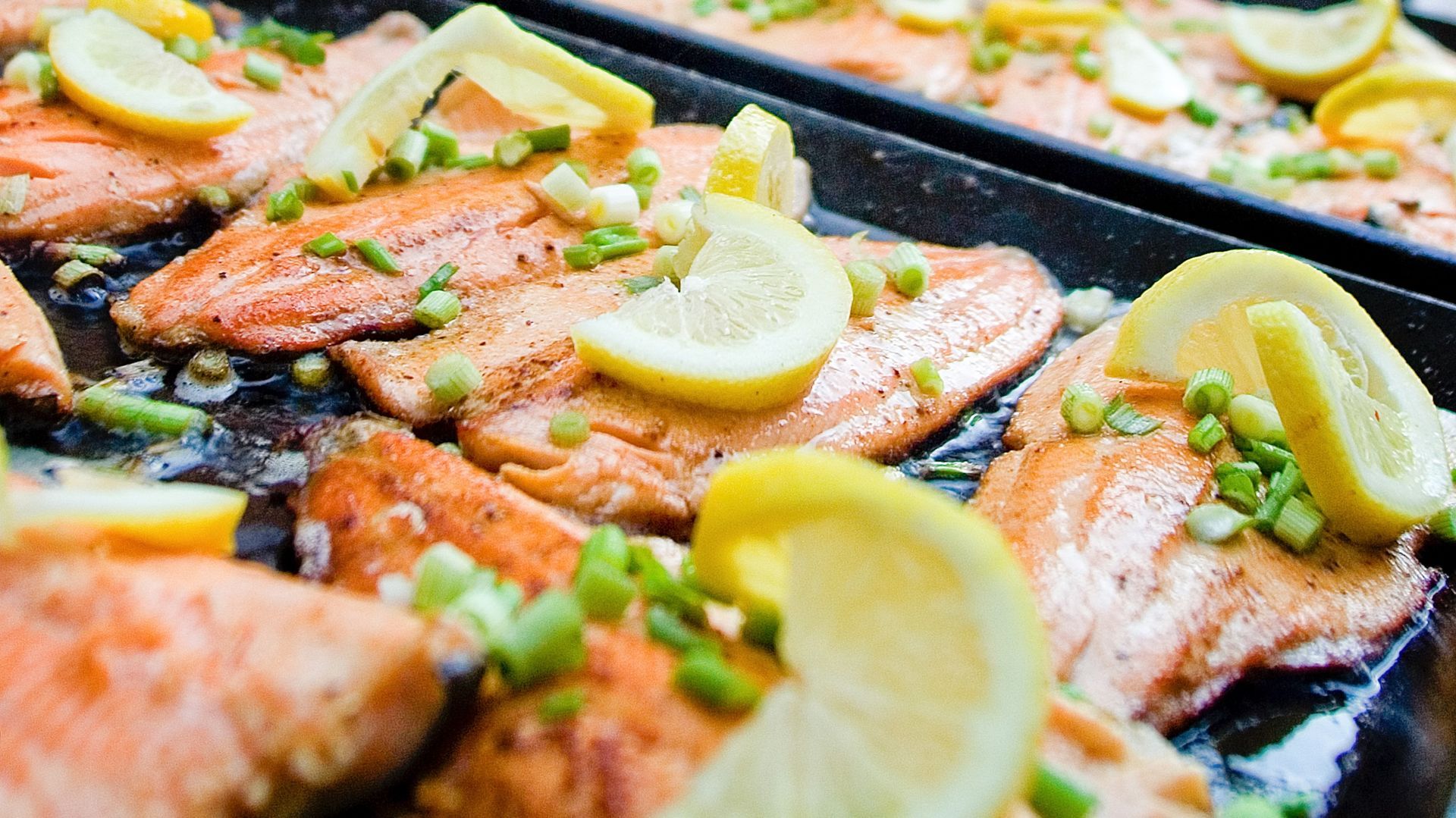 Fish fillets with lemon slices cooking on a griddle