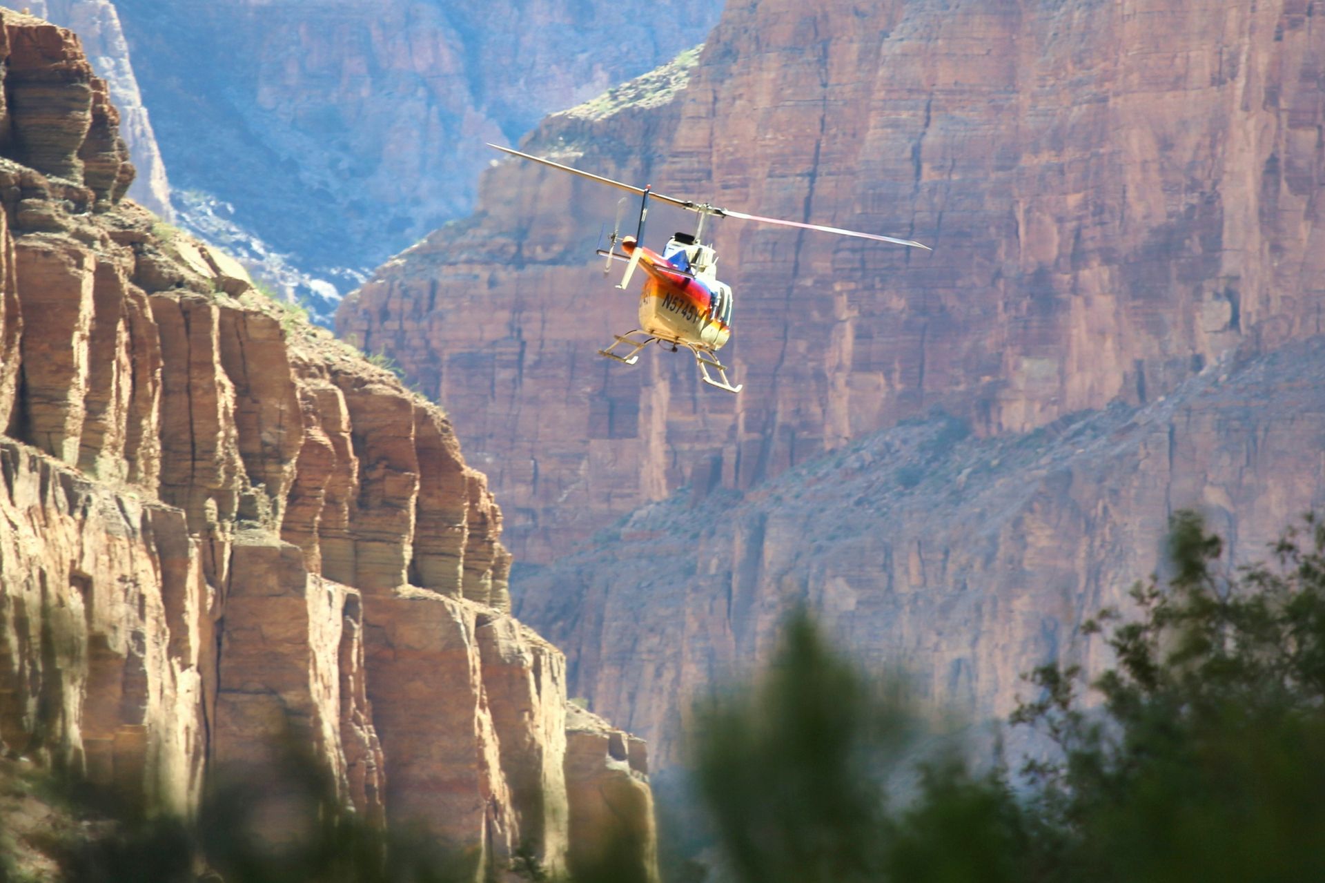 A helicopter flies between Grand Canyon’s cliffs