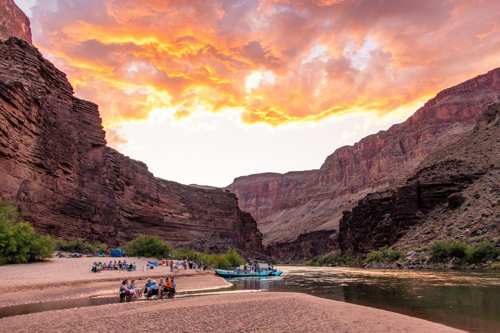 Guests sit together on the beach in the Grand Canyon at a river camp.
