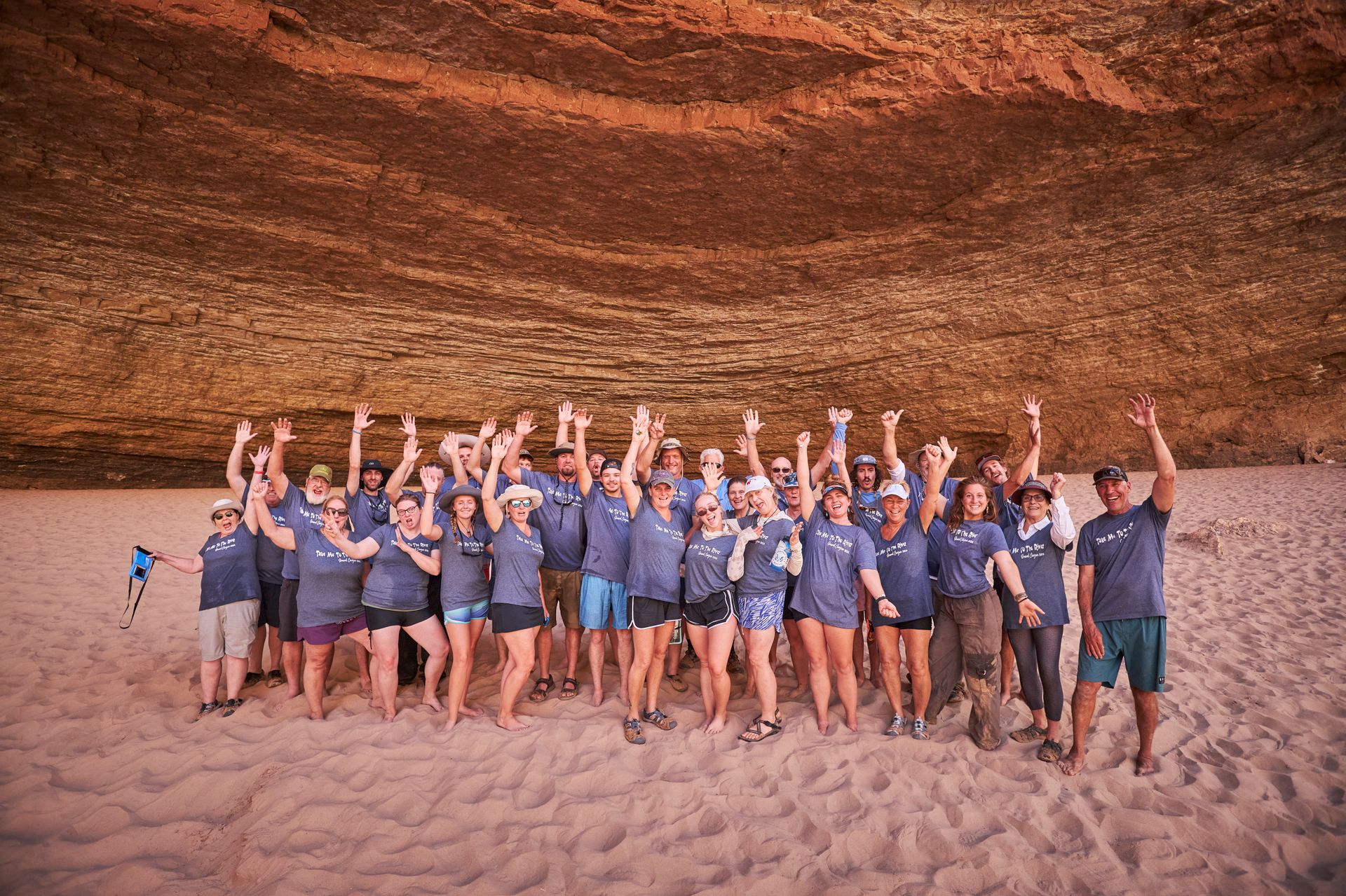 A rafting group poses beneath a broad sandstone overhang