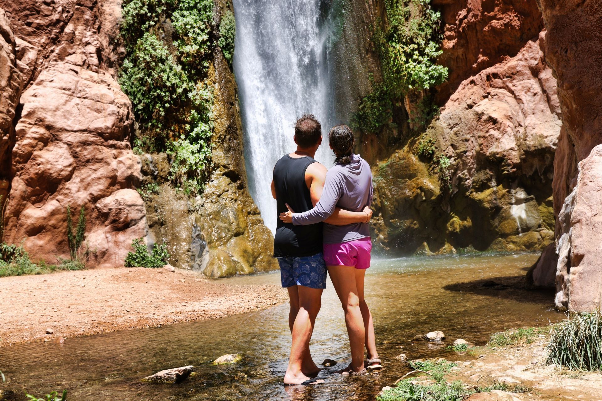 Two visitors stand together below Deer Creek Falls