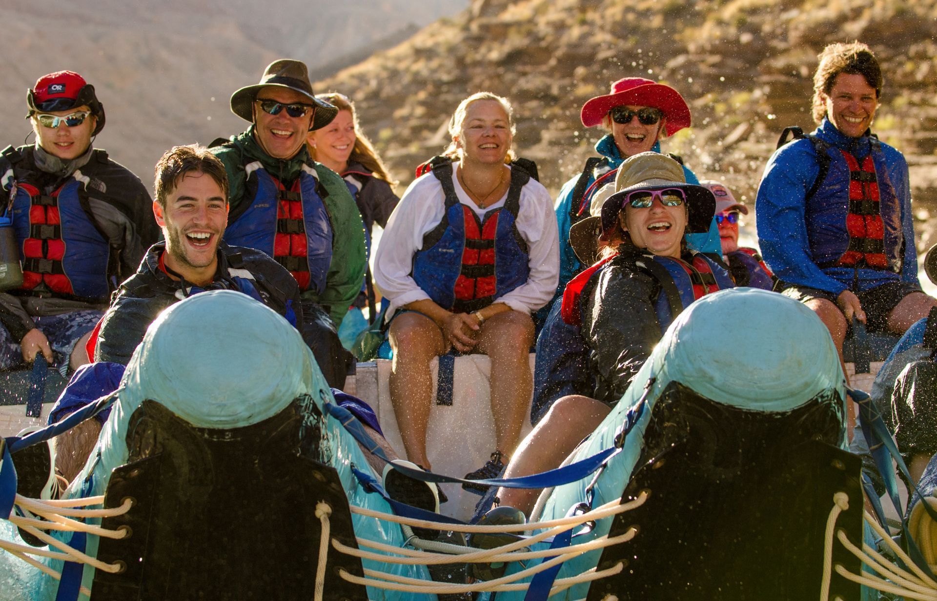 A group of guests riding on a raft and smiling as they look down river.