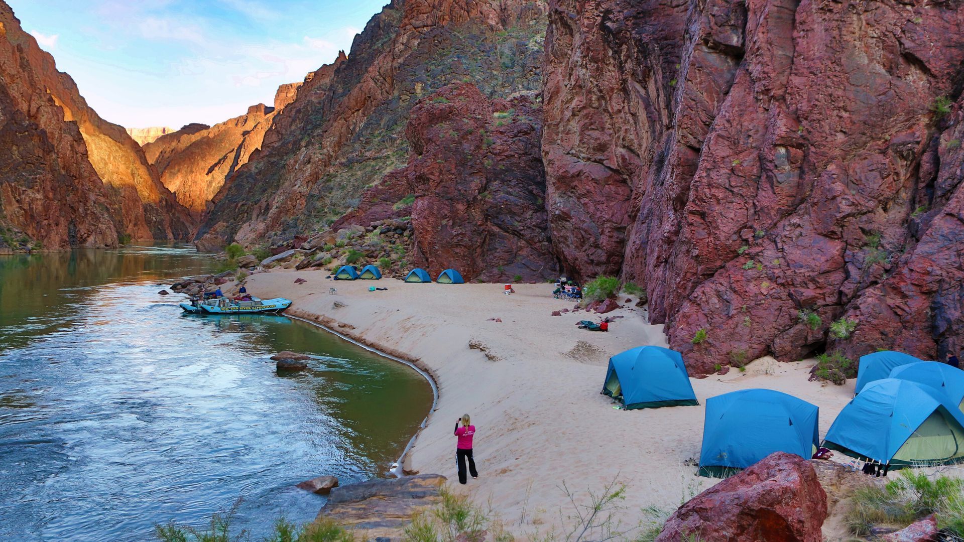 Tents and rafts arranged along a sandy Grand Canyon beach