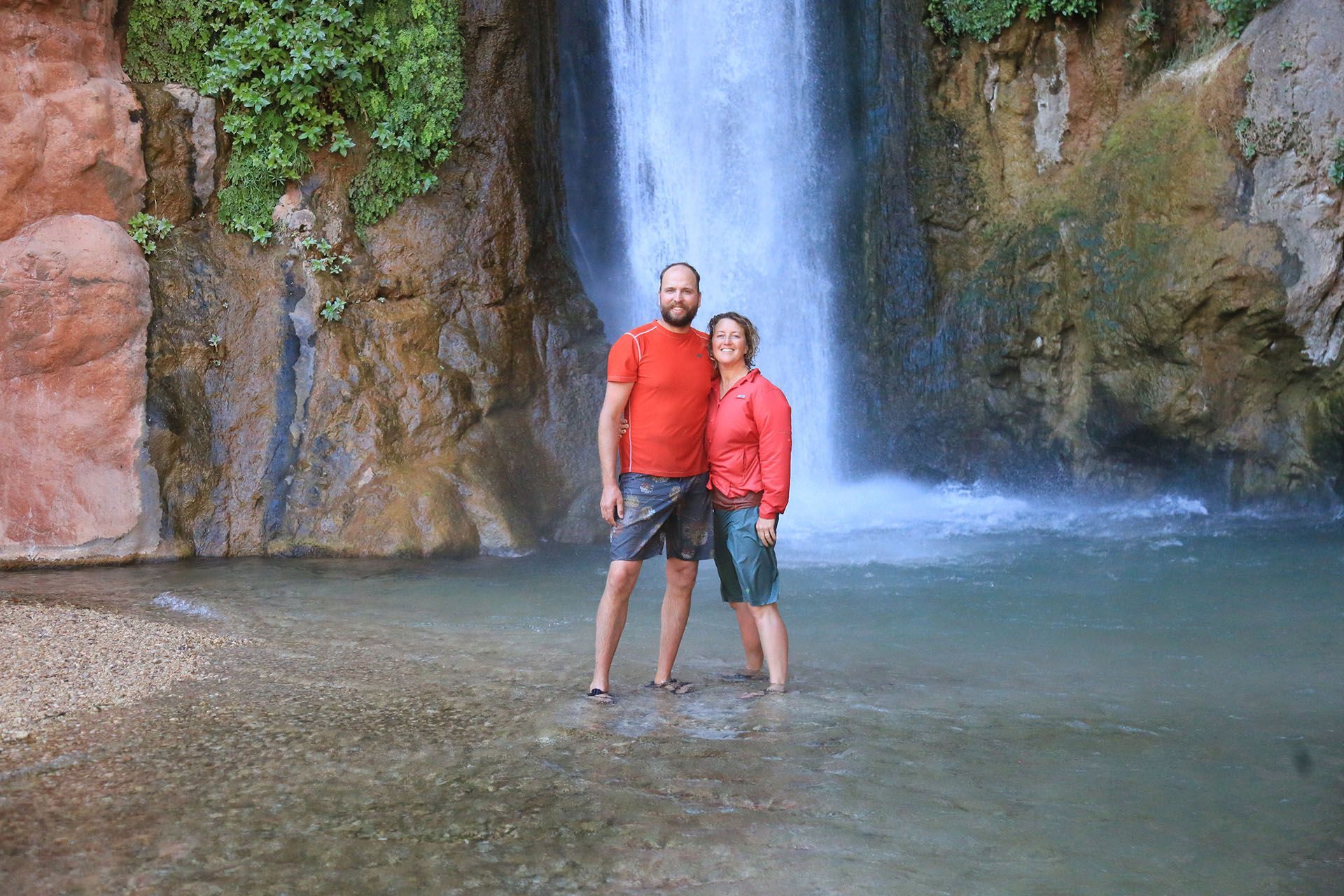 Two visitors stand in the pool below Deer Creek Falls