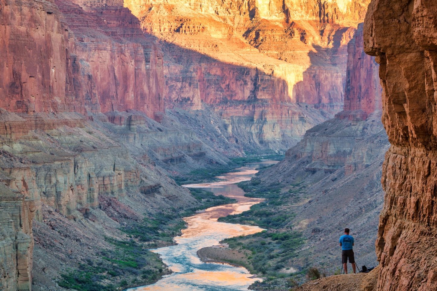 A hiker looks down on the Colorado River from a Nankoweap ledge