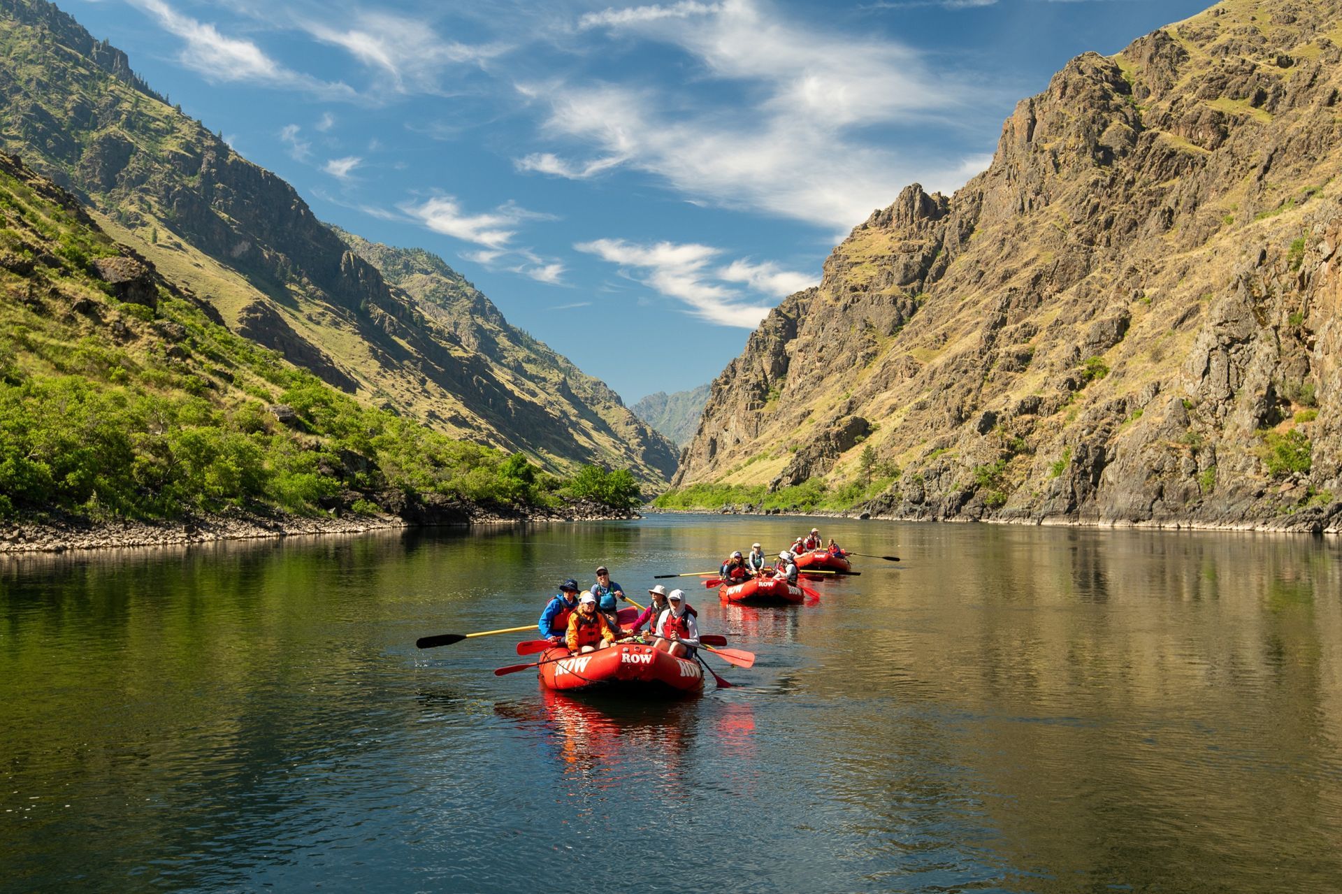 Rafts float between the steep green slopes of Hells Canyon