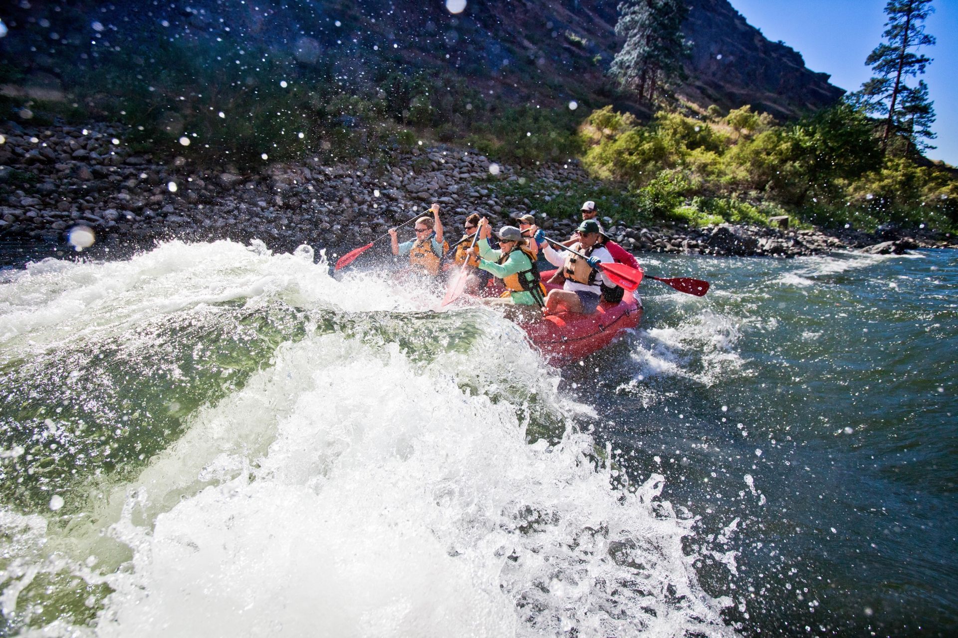 A red raft rides through a breaking whitewater wave