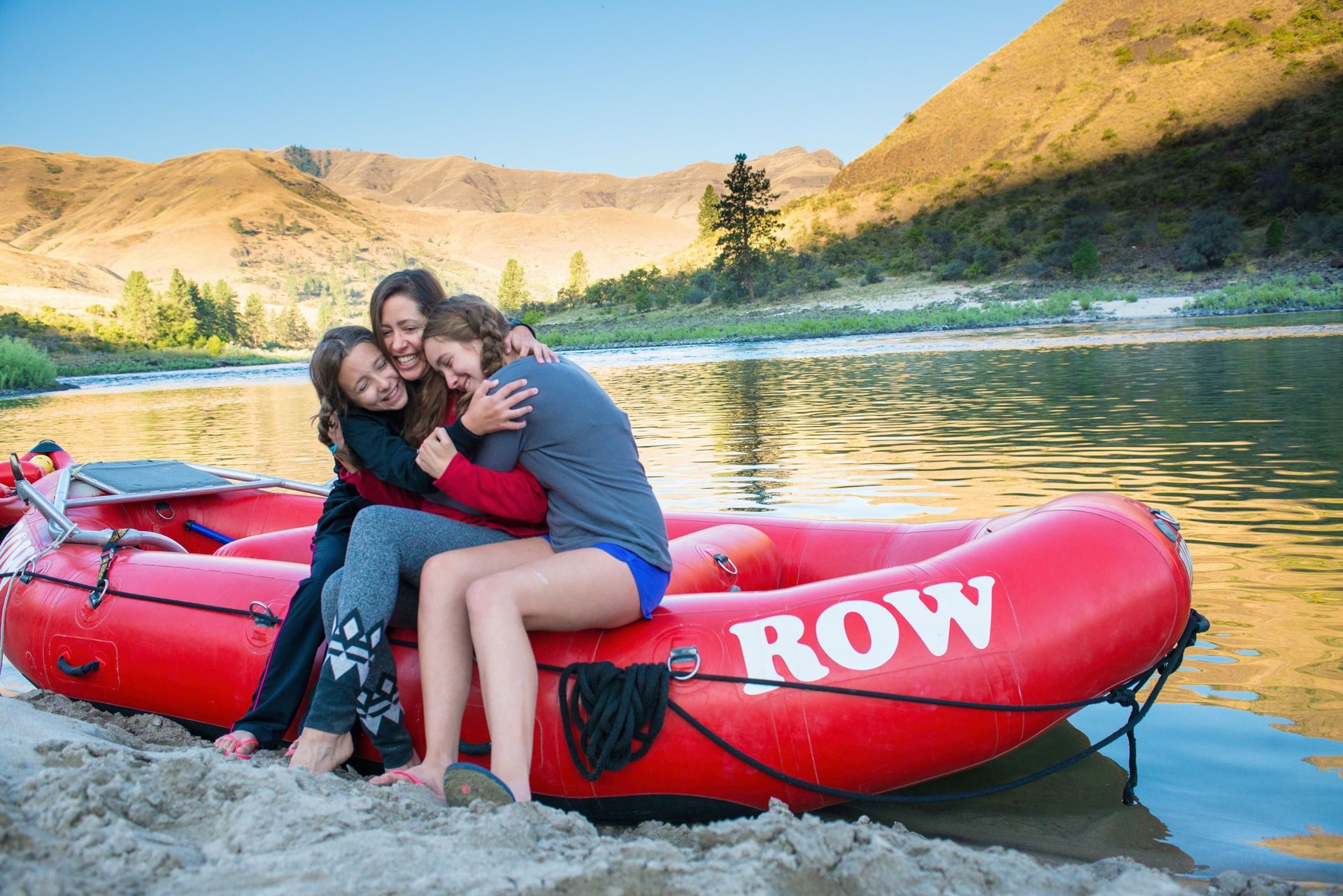 A family hugs on a red raft beside the Lower Salmon River