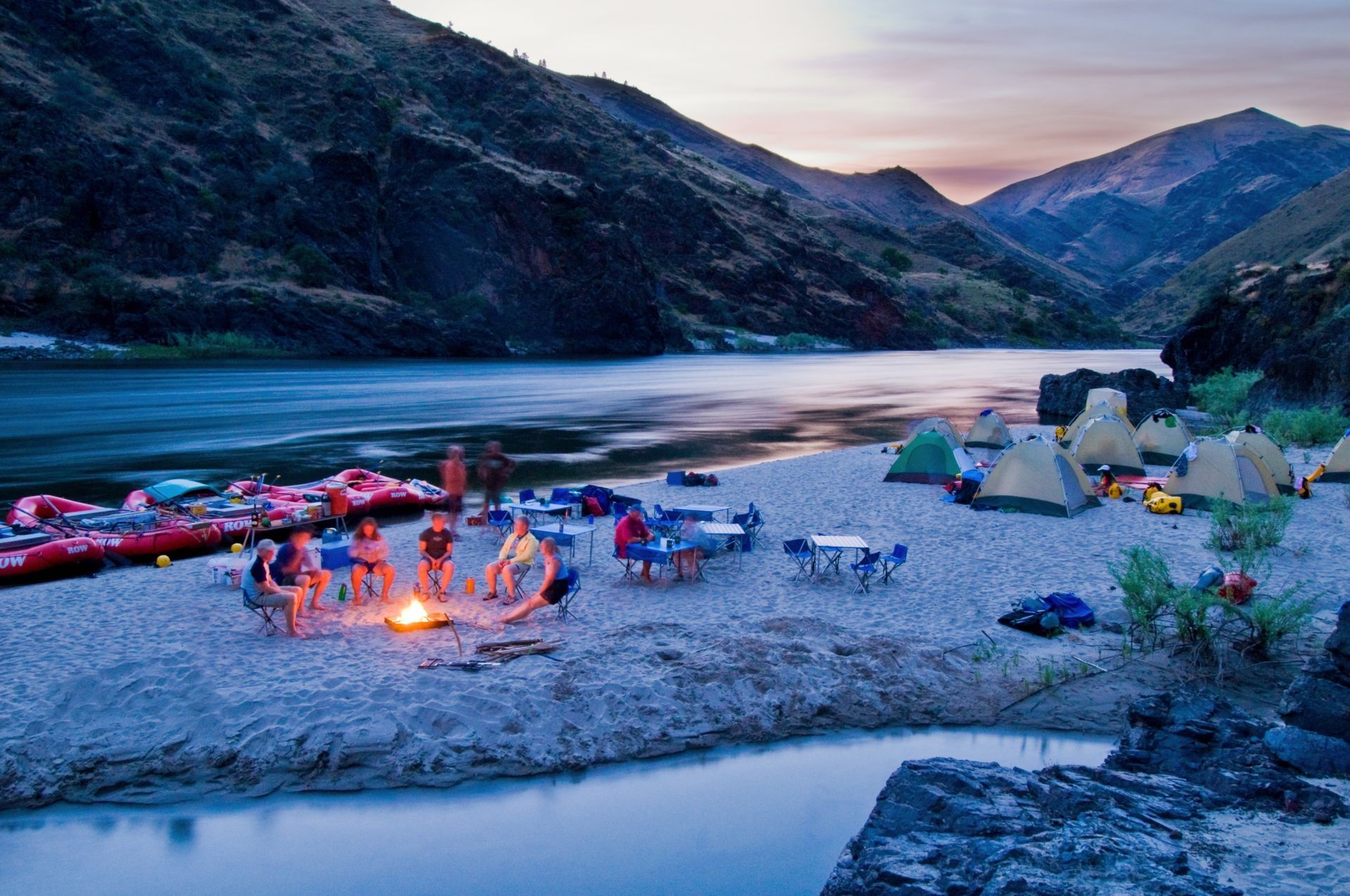 A group gathers around a campfire on a Lower Salmon River beach