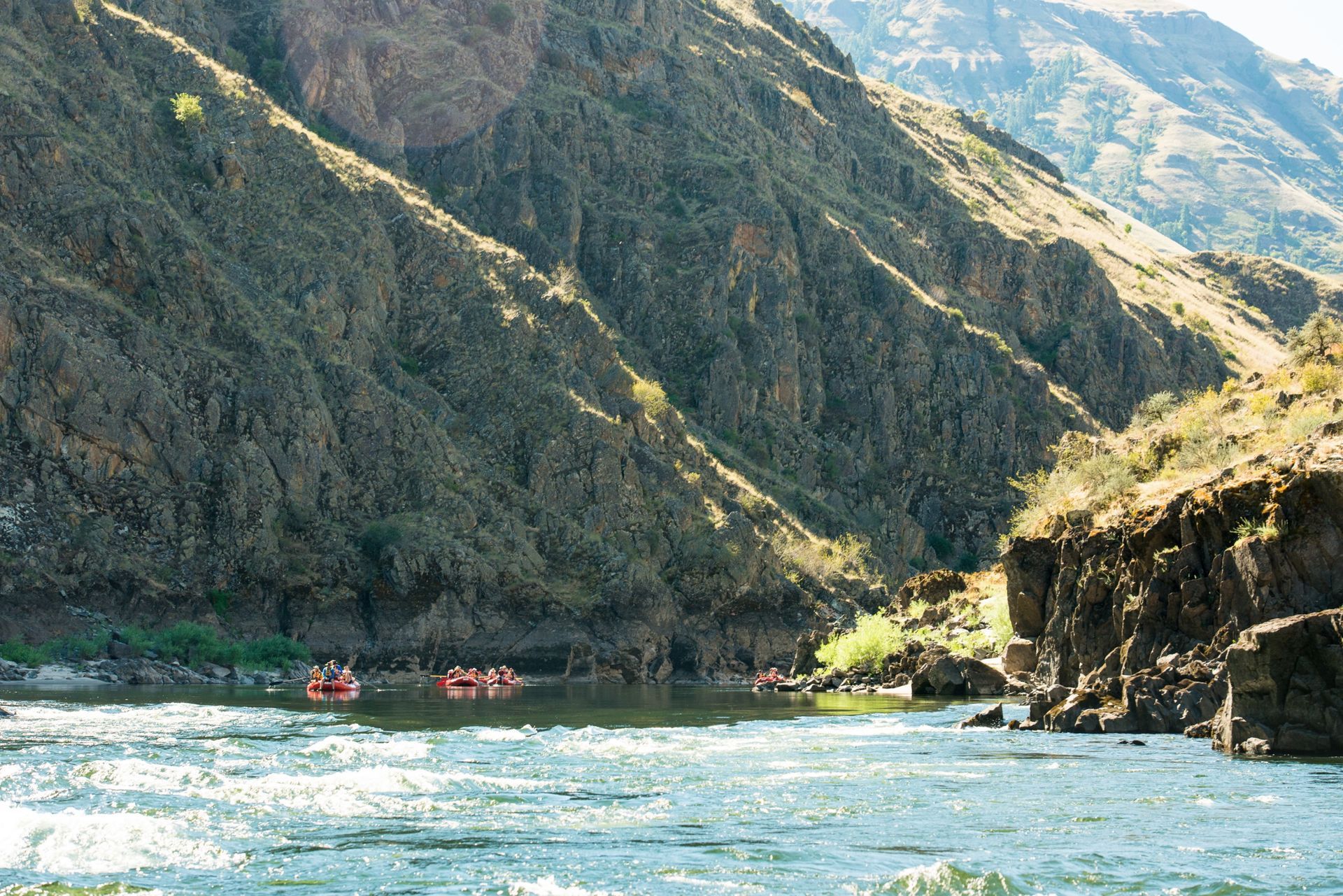 Rafts float below the Lower Salmon River’s steep canyon slopes