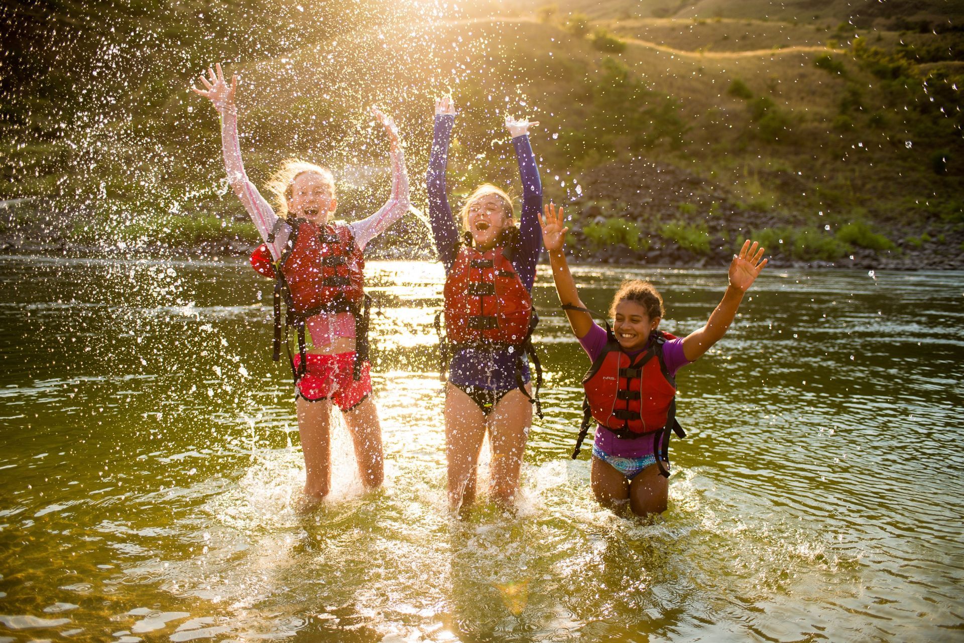 Three rafters throw water into the air while standing in the river