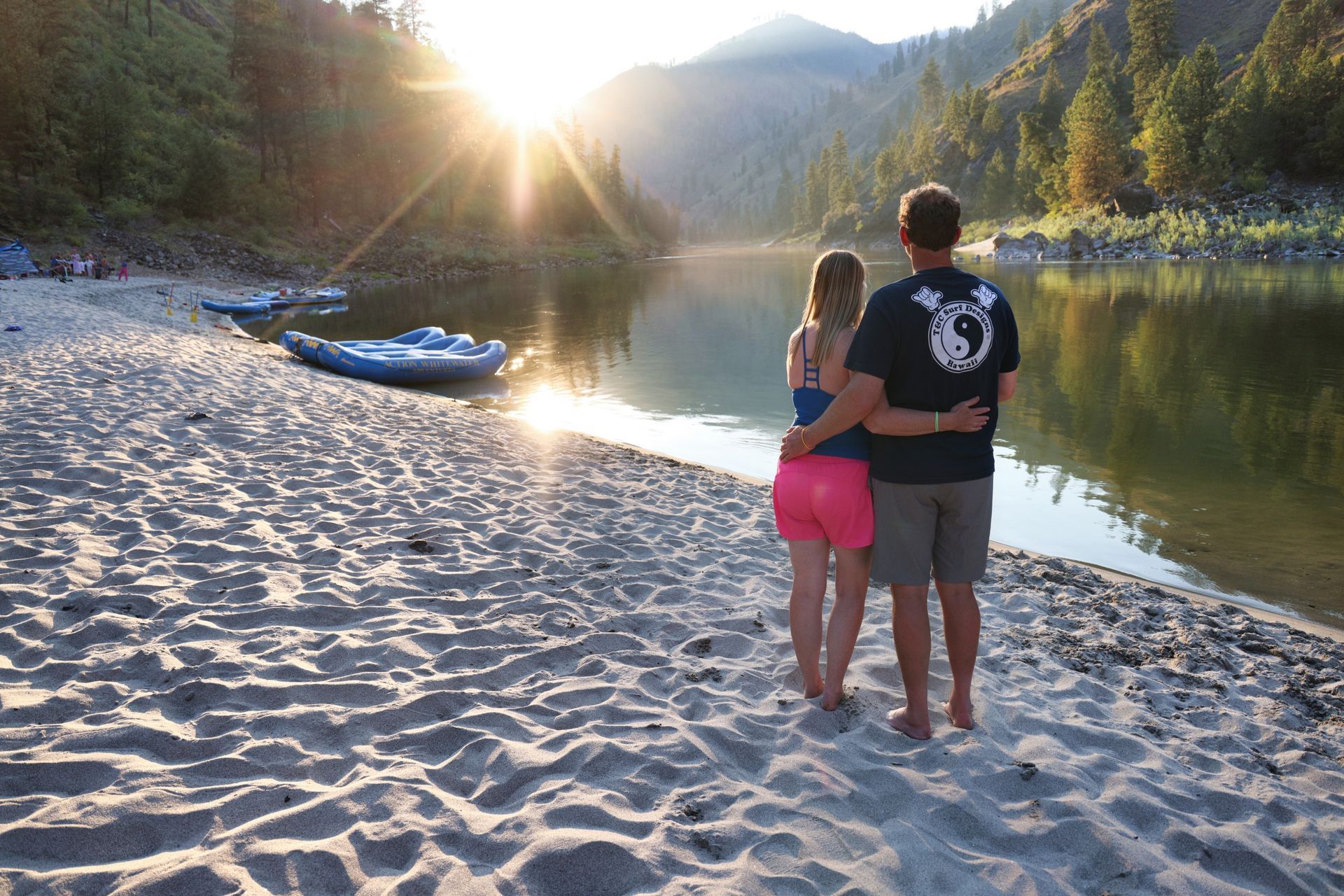 Two people stand together on a sandy Salmon River beach at sunset