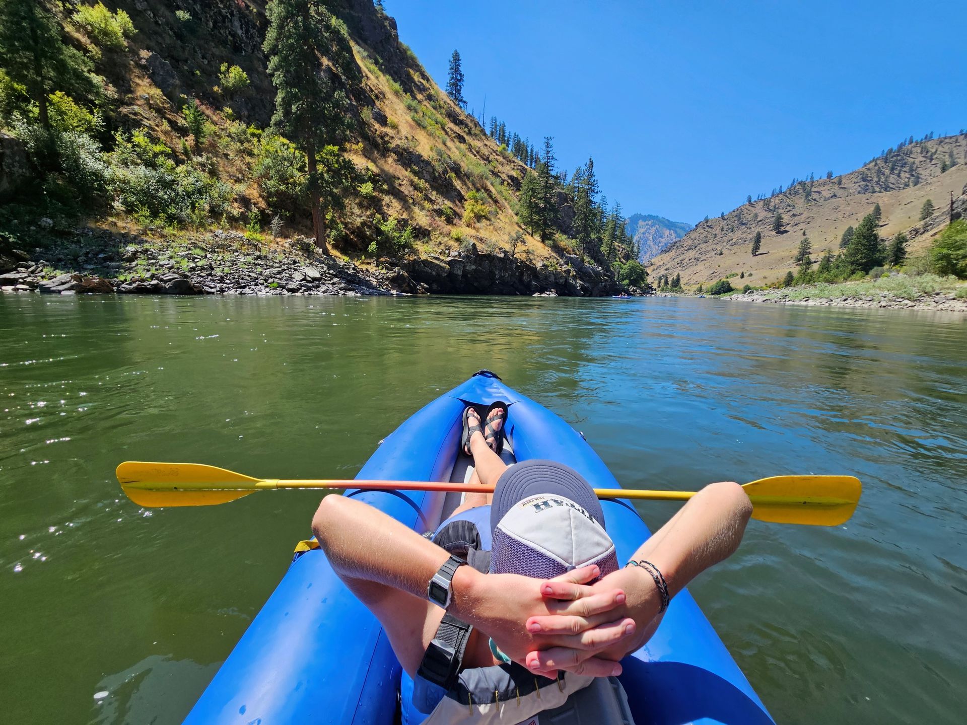 A kayaker reclines on an inflatable kayak on calm water