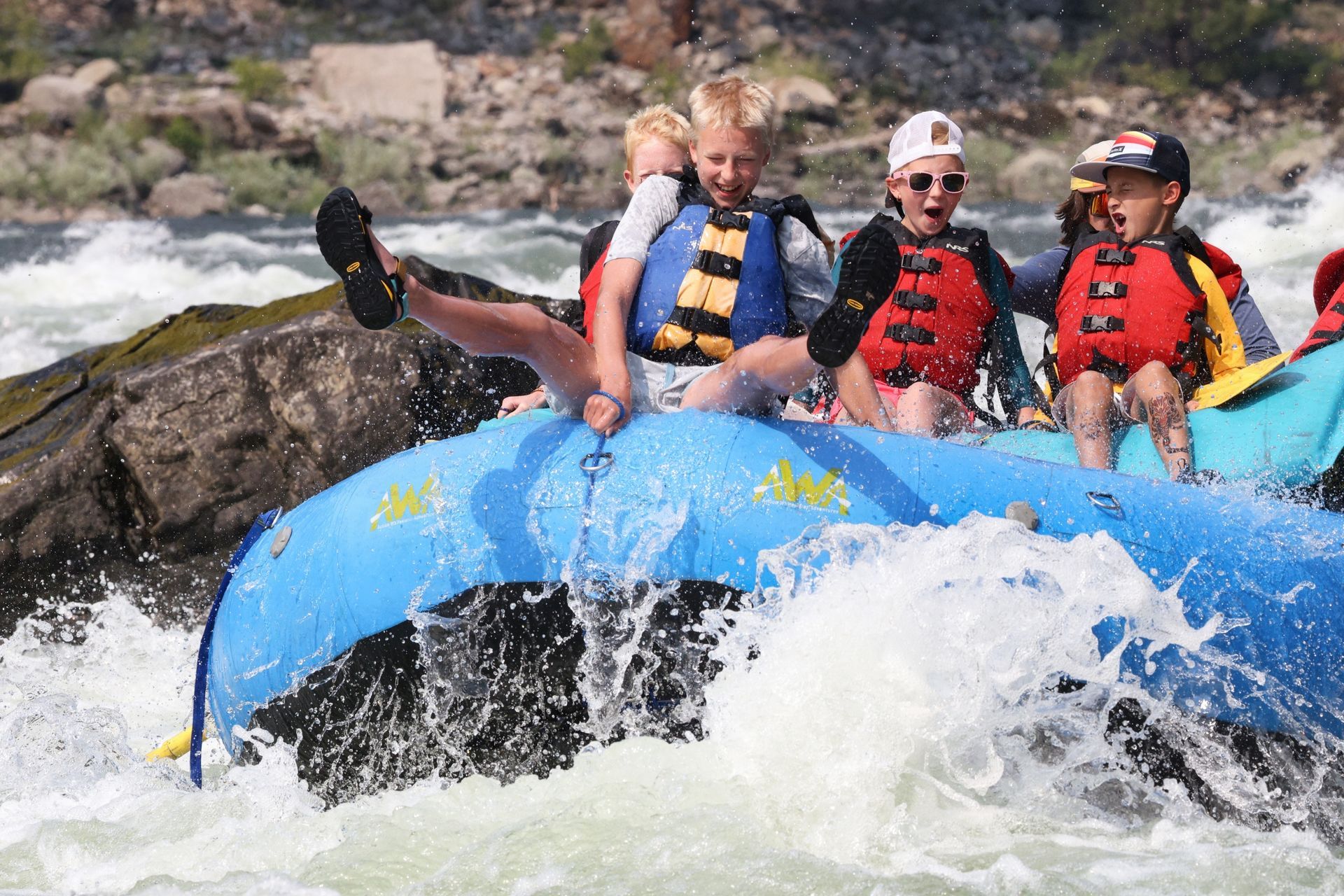 Guests ride the front of an oar raft through a whitewater wave