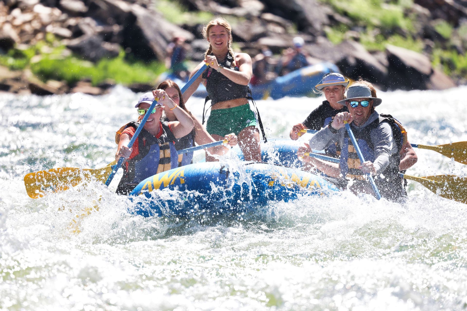 A blue paddle raft splashes through a Salmon River rapid