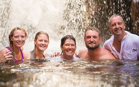 A family smiles together in a riverside pool