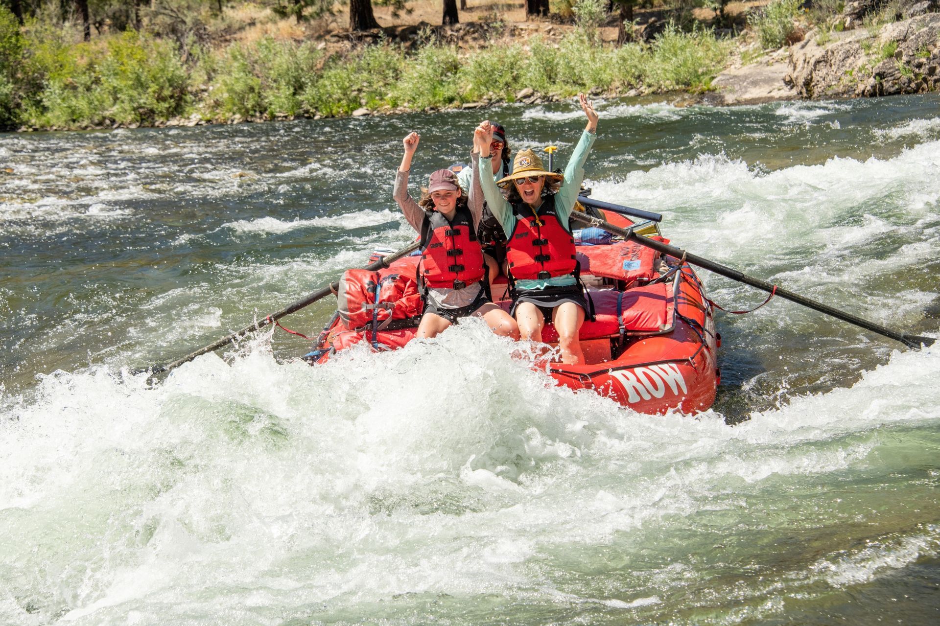 Two rafters lift their arms as their raft runs a rapid