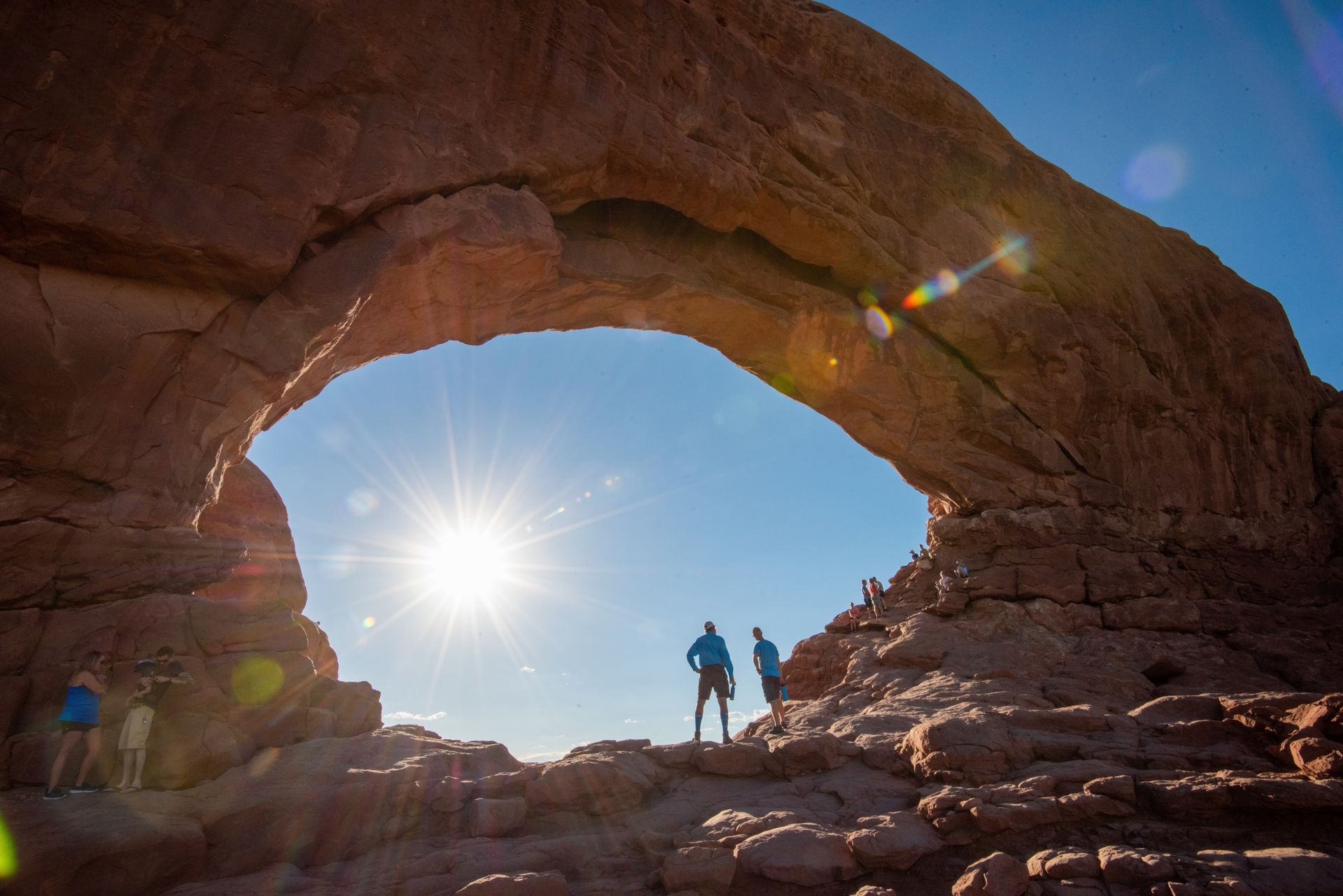 Hikers silhouetted beneath a natural sandstone arch