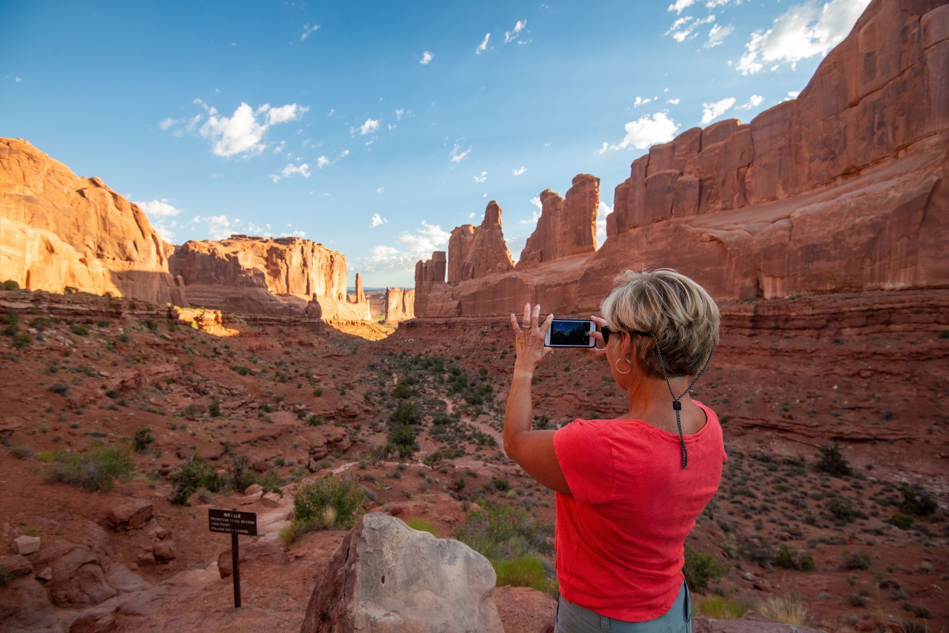 A visitor photographs the sandstone towers at Park Avenue