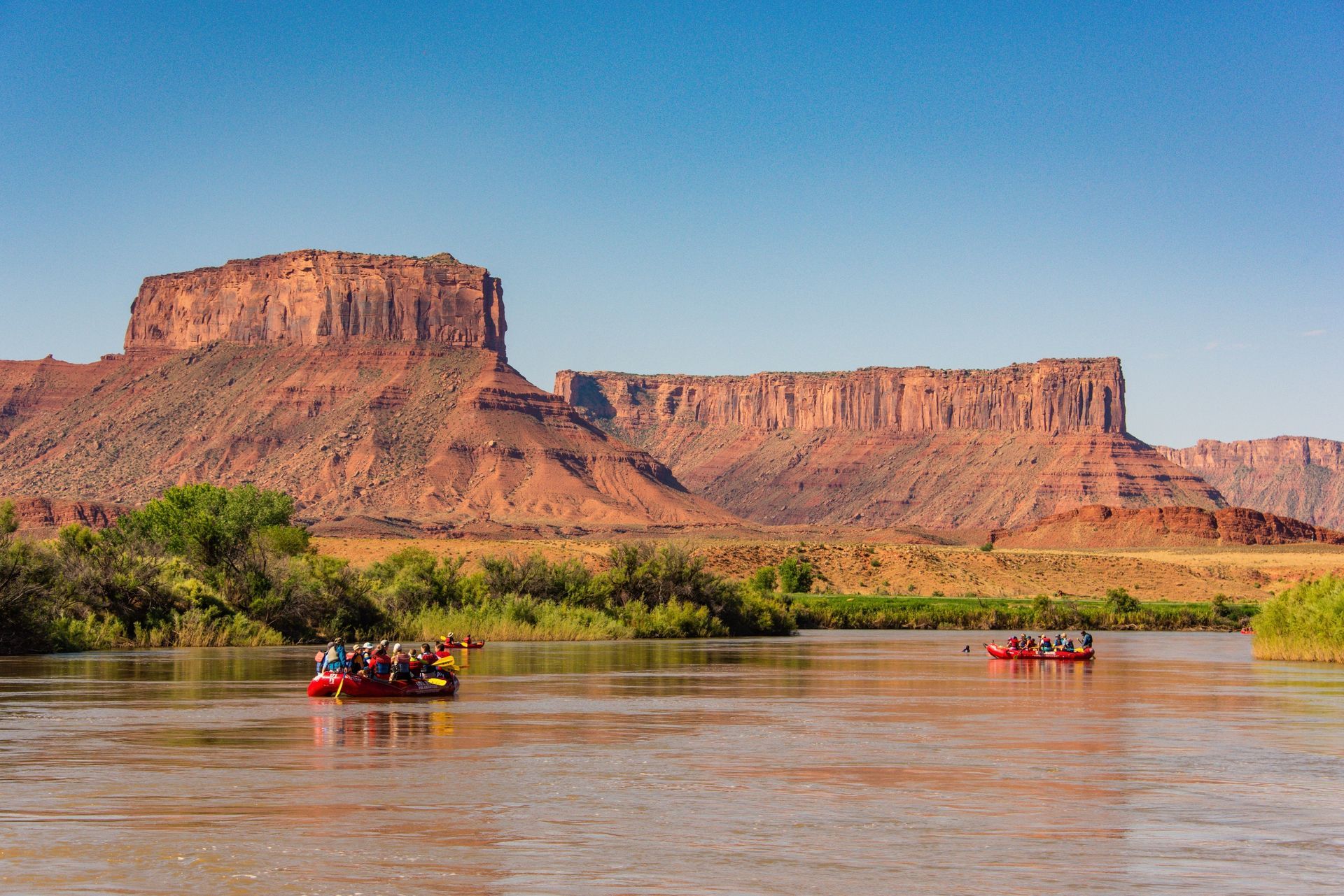 Rafts float down the Colorado River beneath Castle Valley’s red rock formations