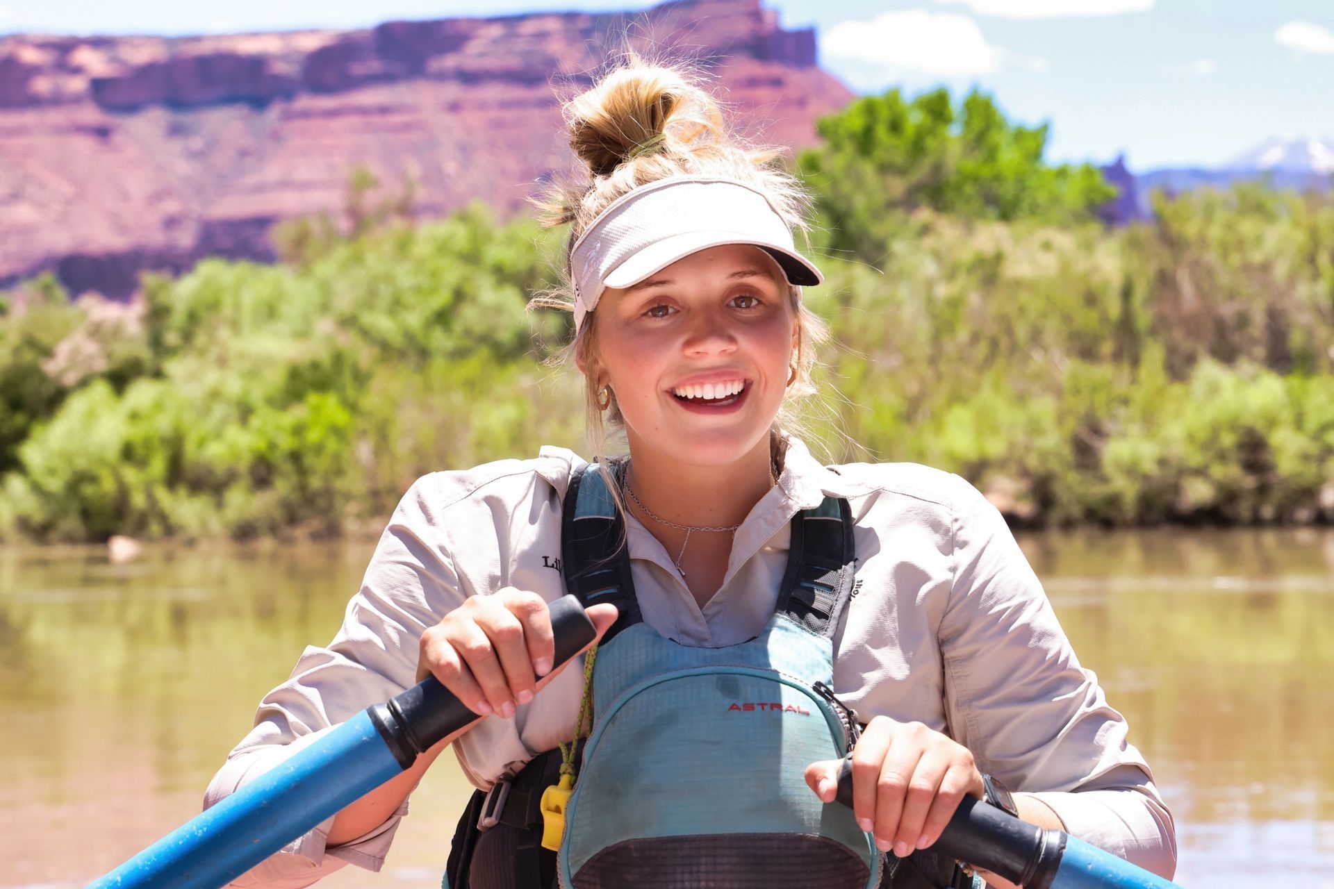 A smiling guide rows a raft on the Colorado River
