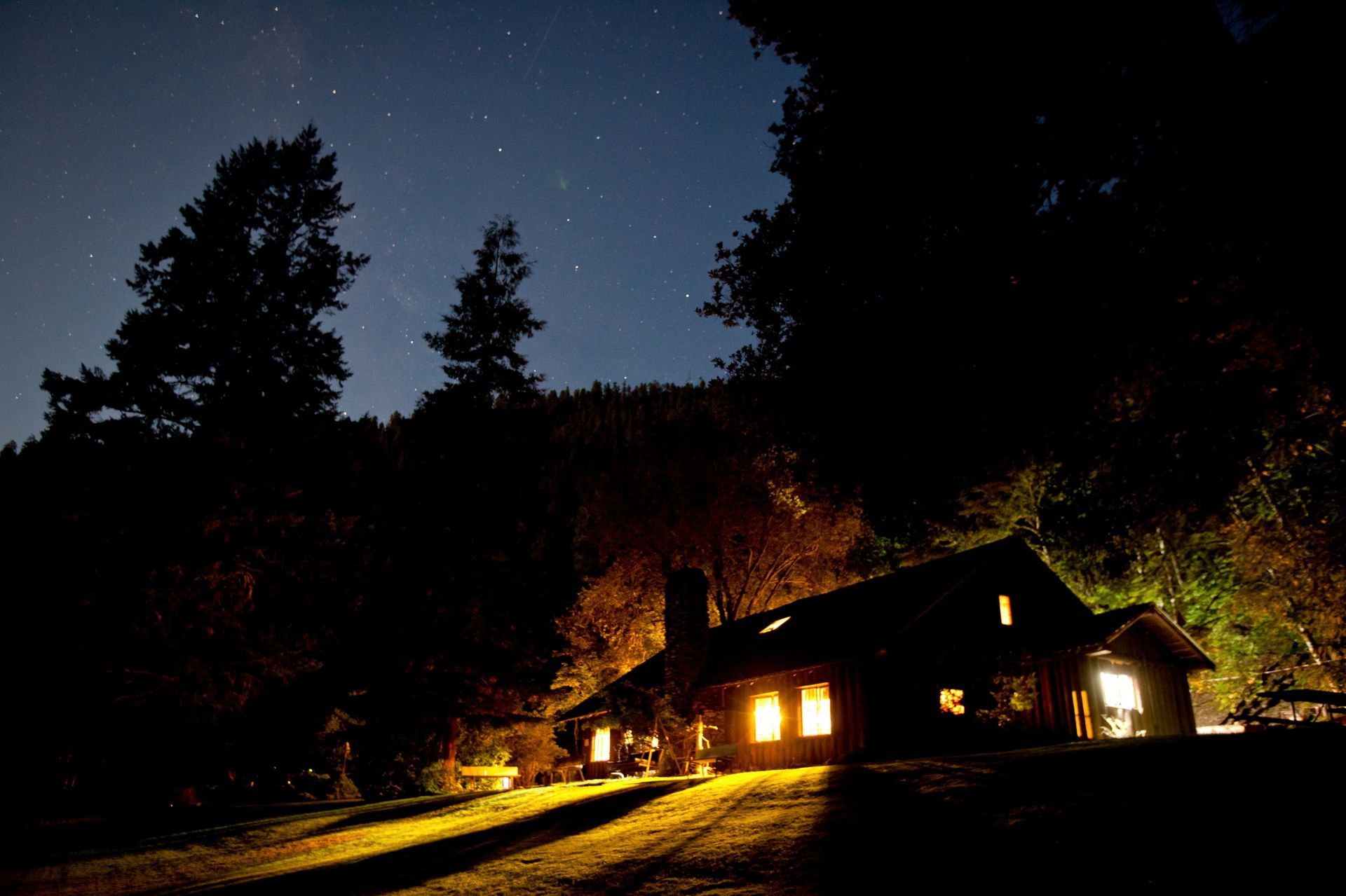 Black Bar Lodge lit at night among riverside trees