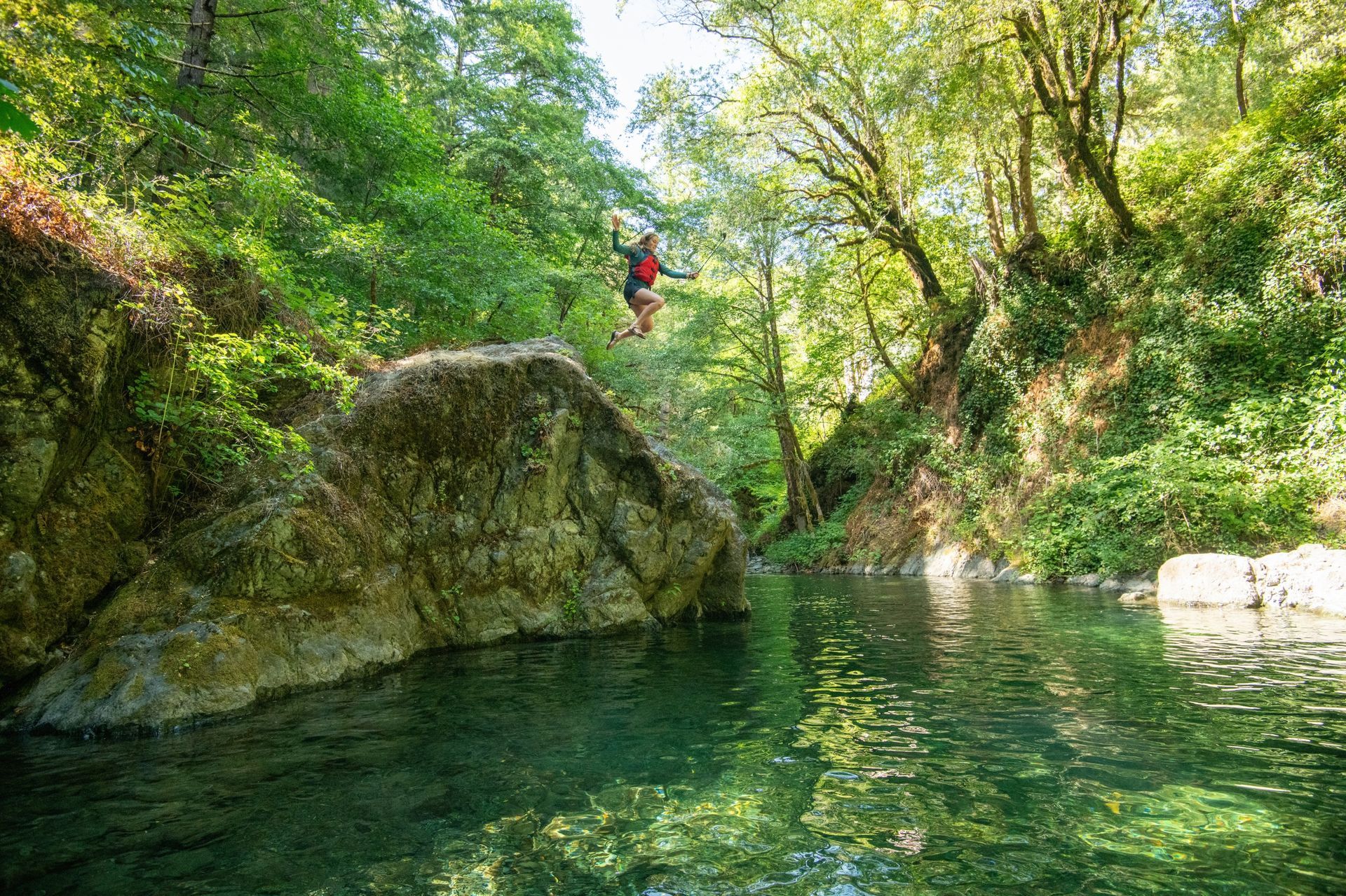 Clear swimming pool between mossy rocks in the forest