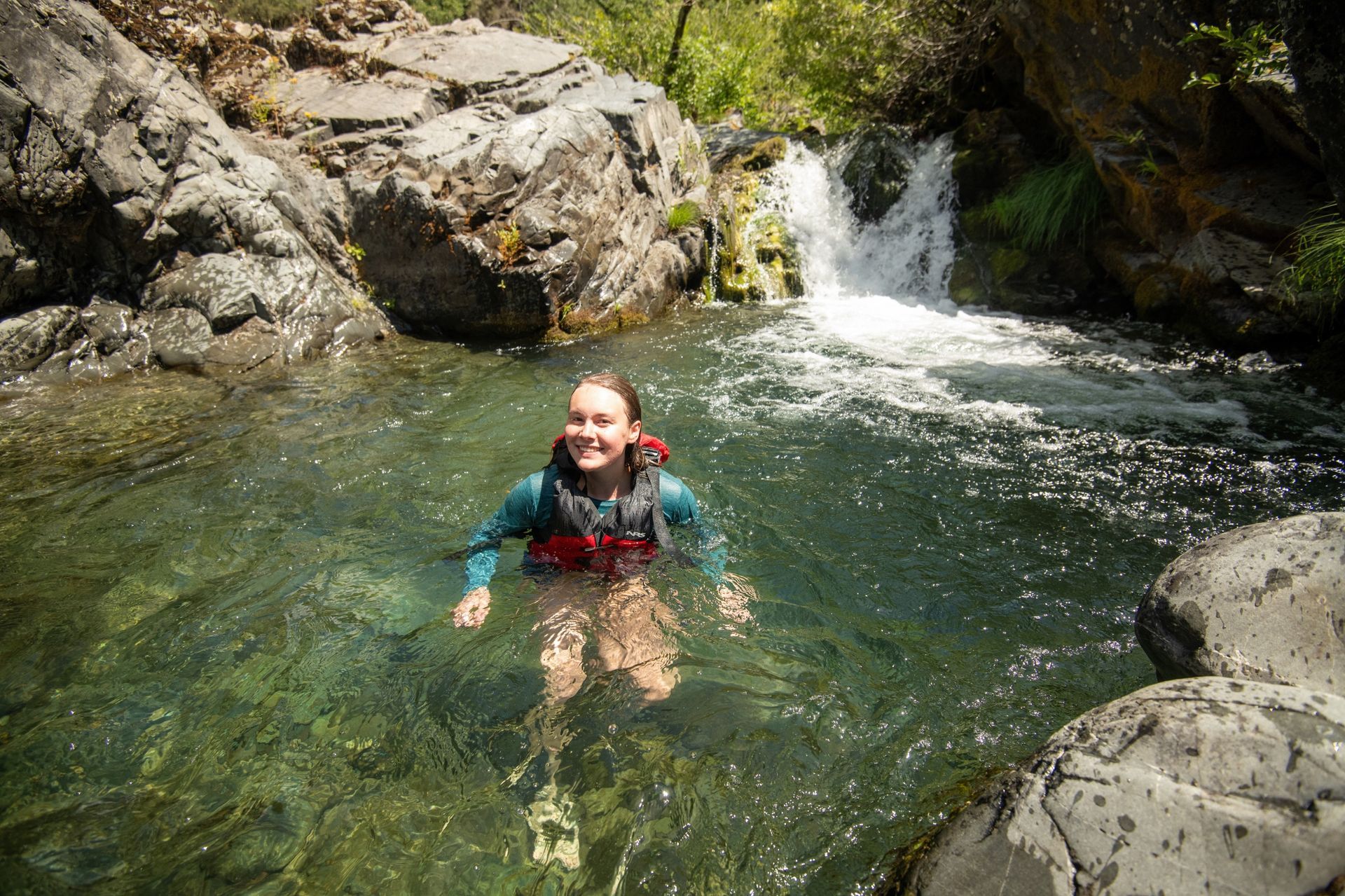 A swimmer in a pool below a small waterfall