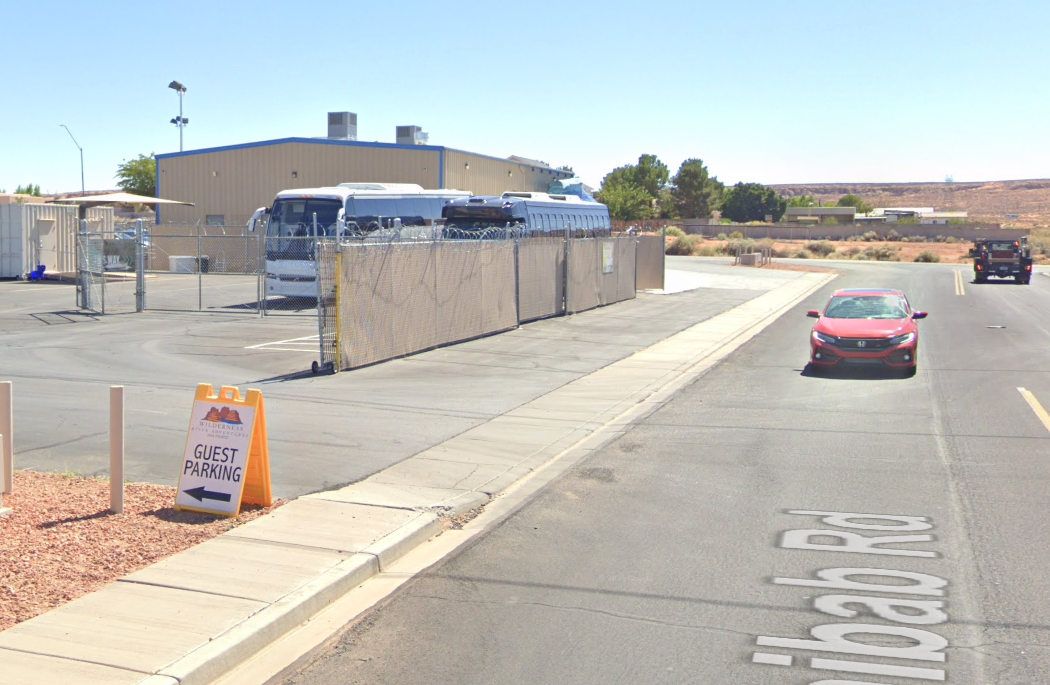 Guest parking entrance at Wilderness River Shuttle in Page, Arizona, with a yellow parking sign.