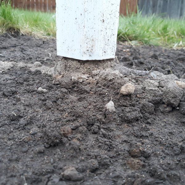 A white pole is sitting in the middle of a pile of dirt.