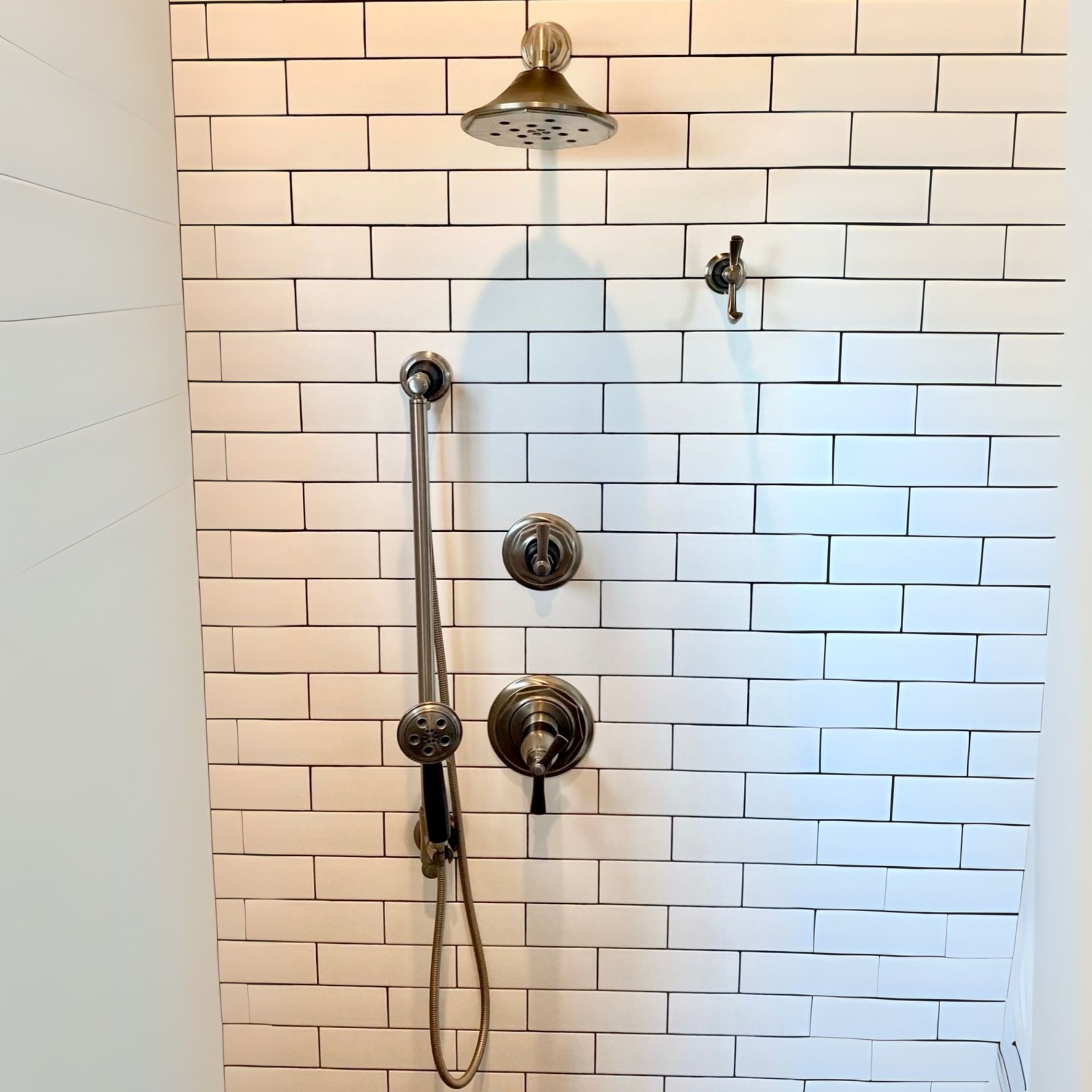 E.Squared Custom Plumbing Heating and Air - Shower with white brick-like tile, a rain shower head, handheld shower.