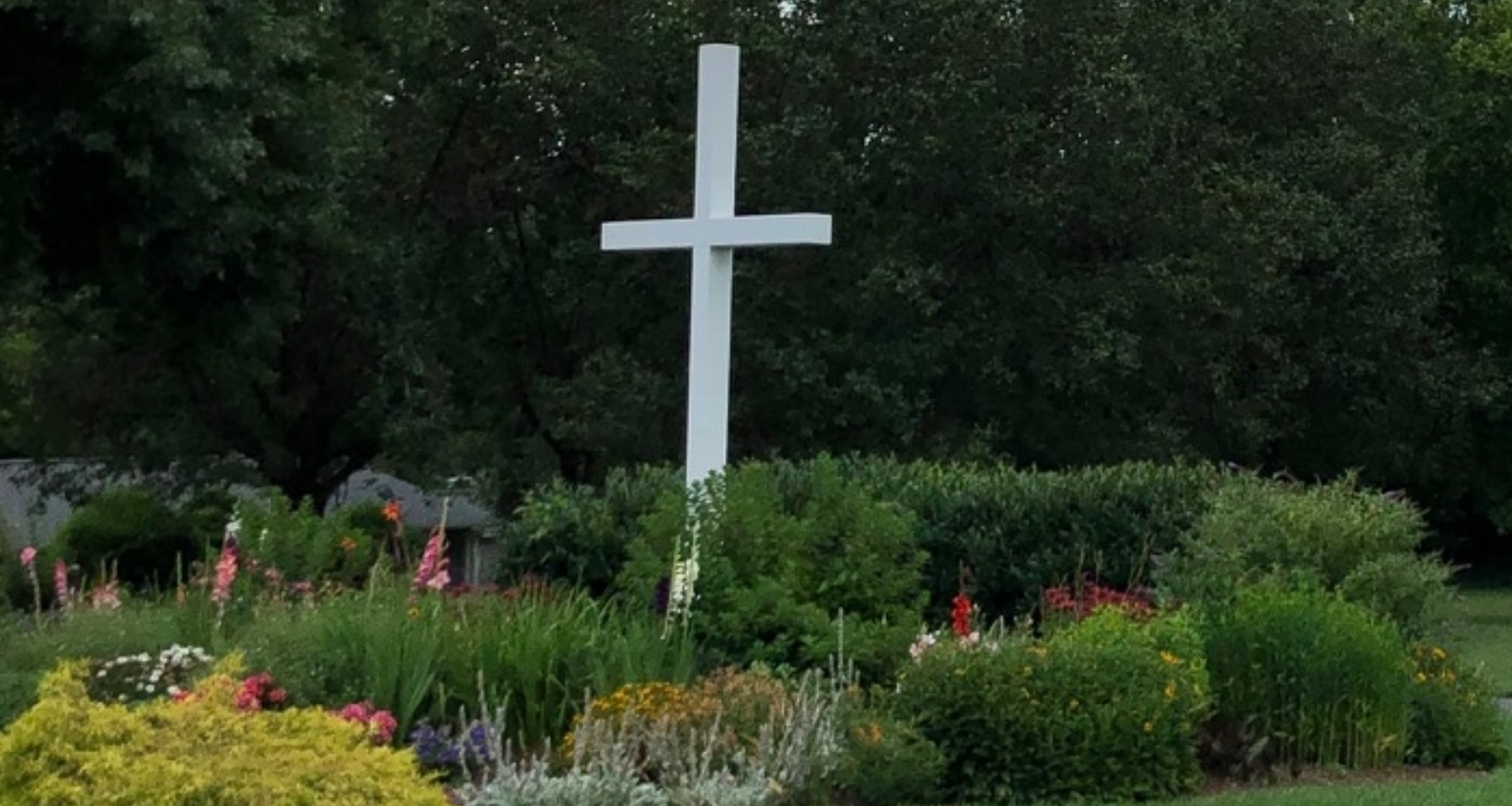 A large white cross in the middle of a garden