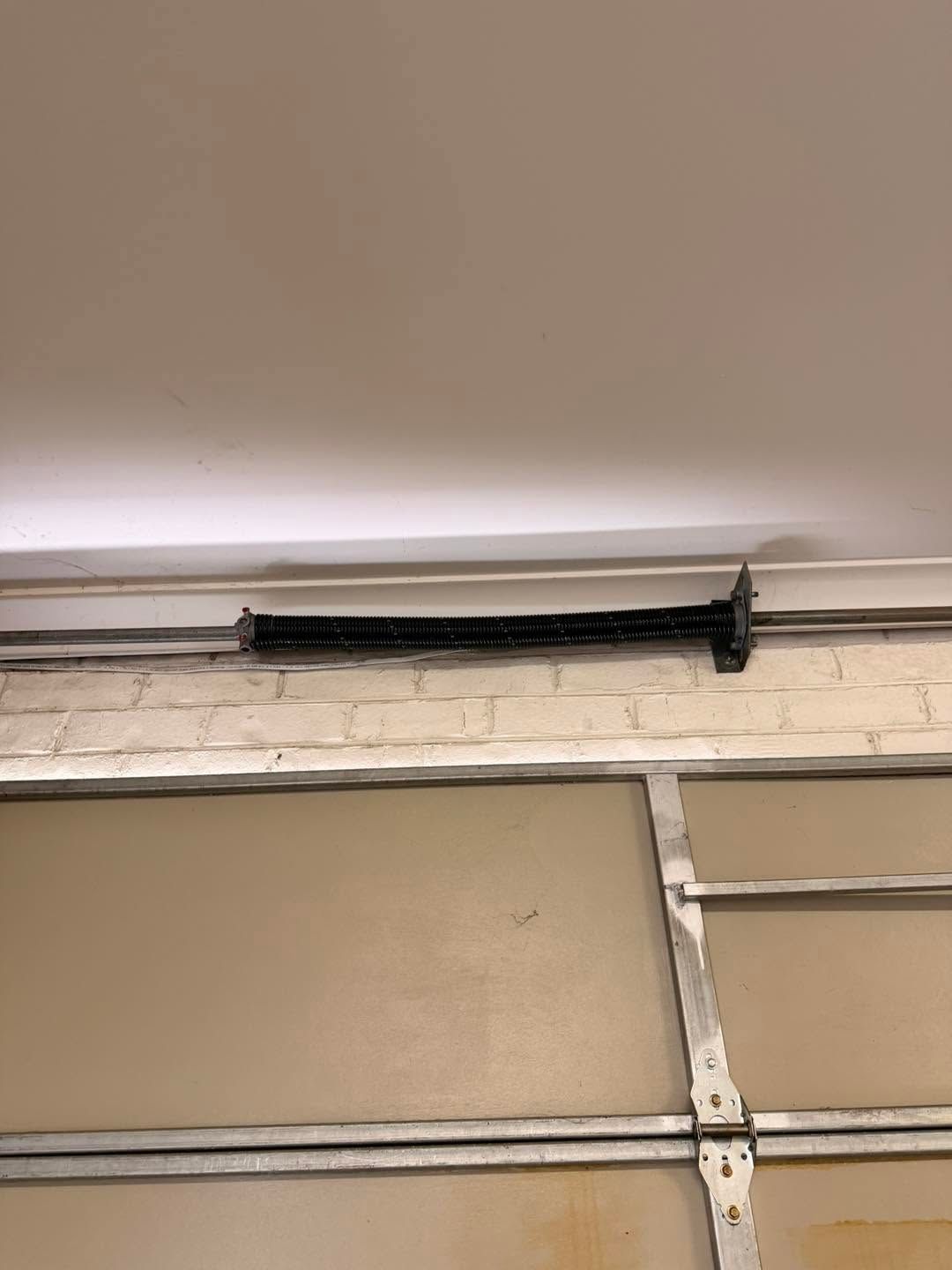 Black curtain rod mounted above a garage door against a beige wall