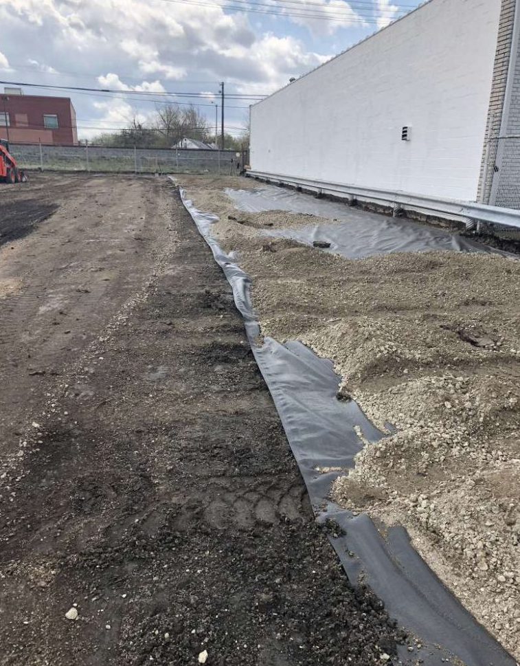 A large white building is sitting on top of a dirt field.