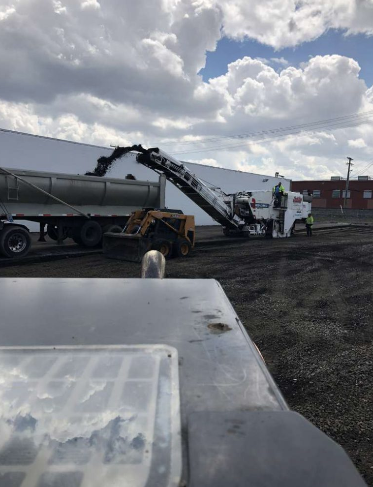 A truck is being loaded with gravel in front of a building.