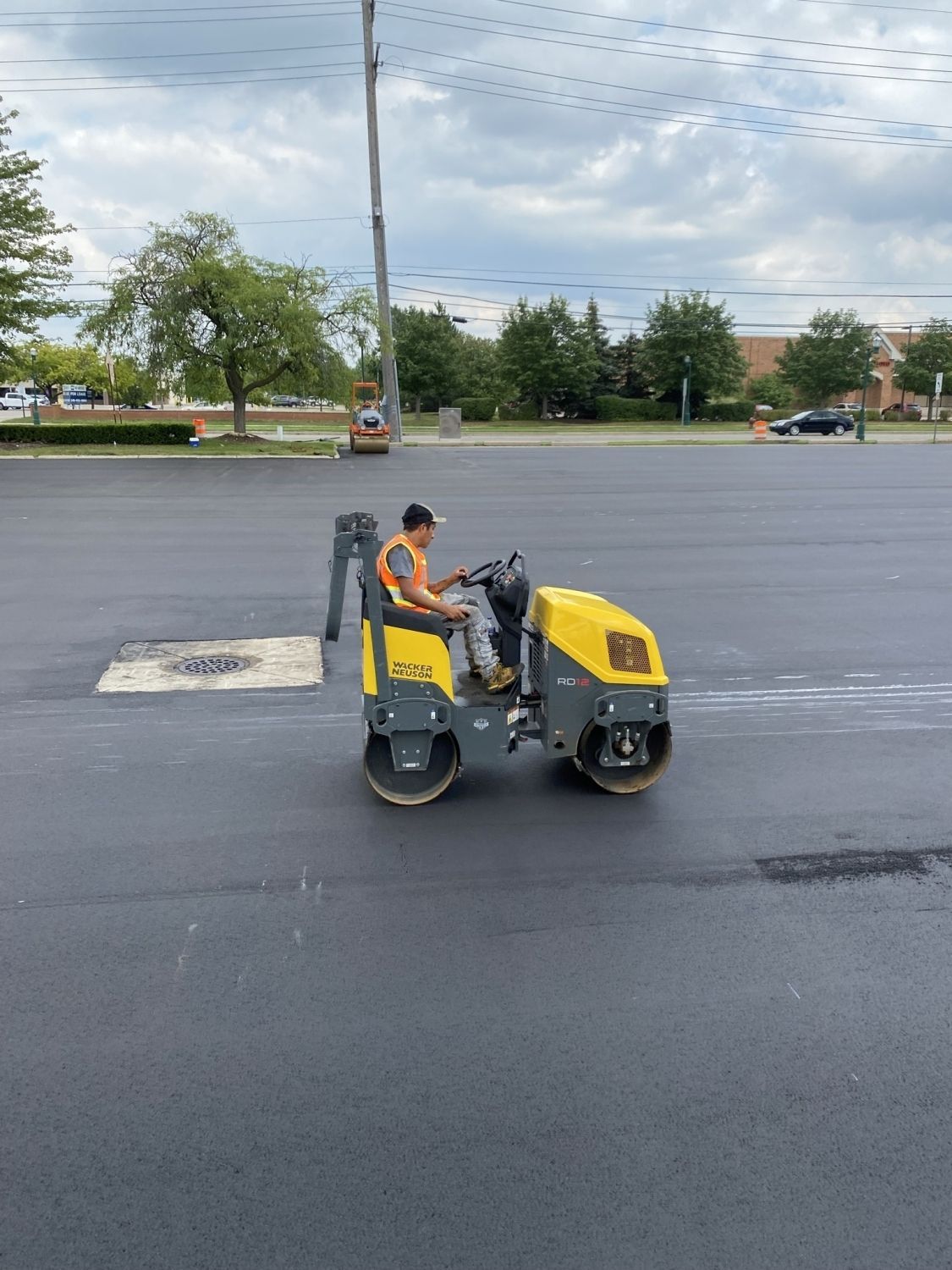 A man is driving a yellow roller on a road.