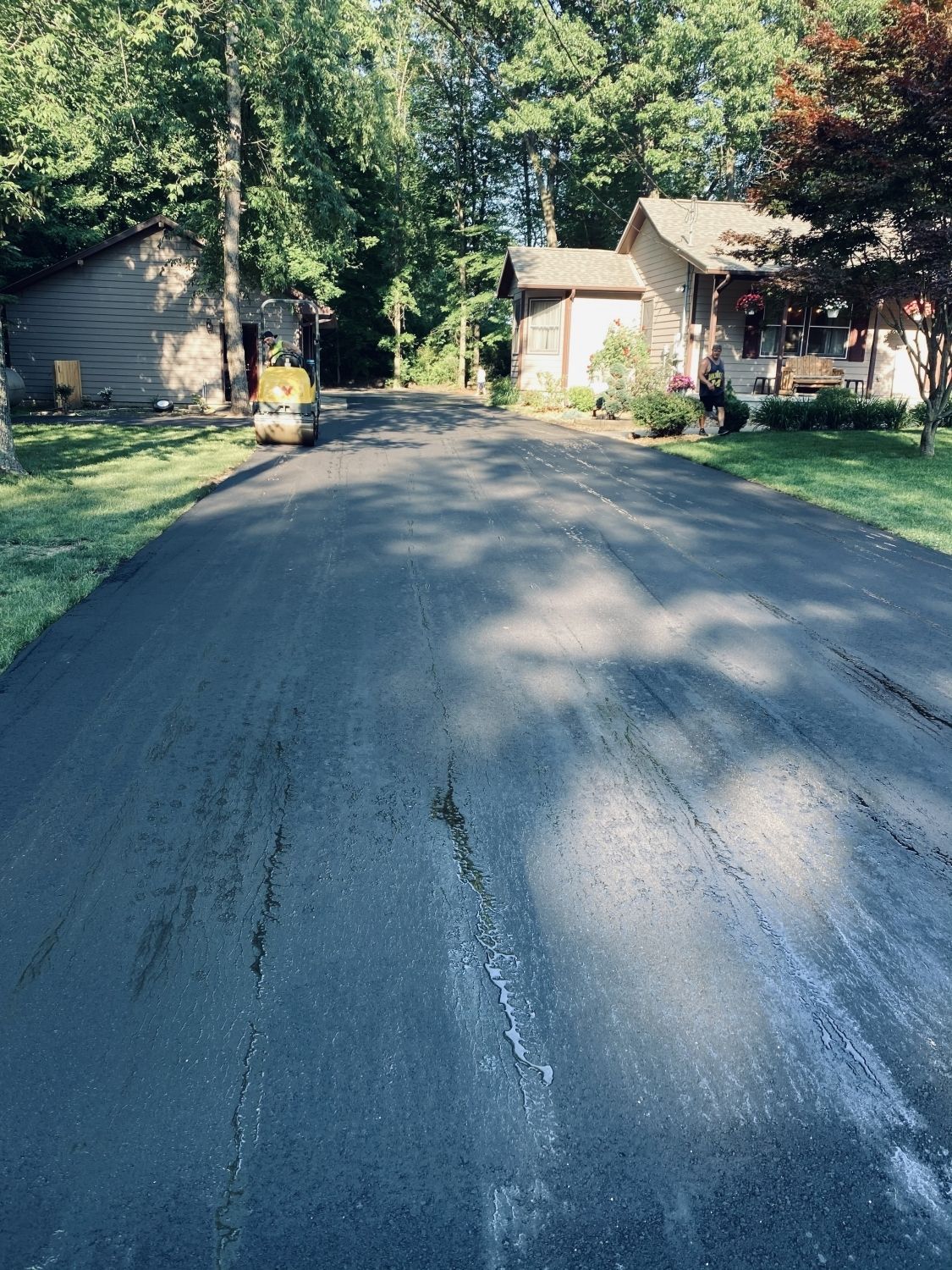 A asphalt driveway is being paved in front of a house.